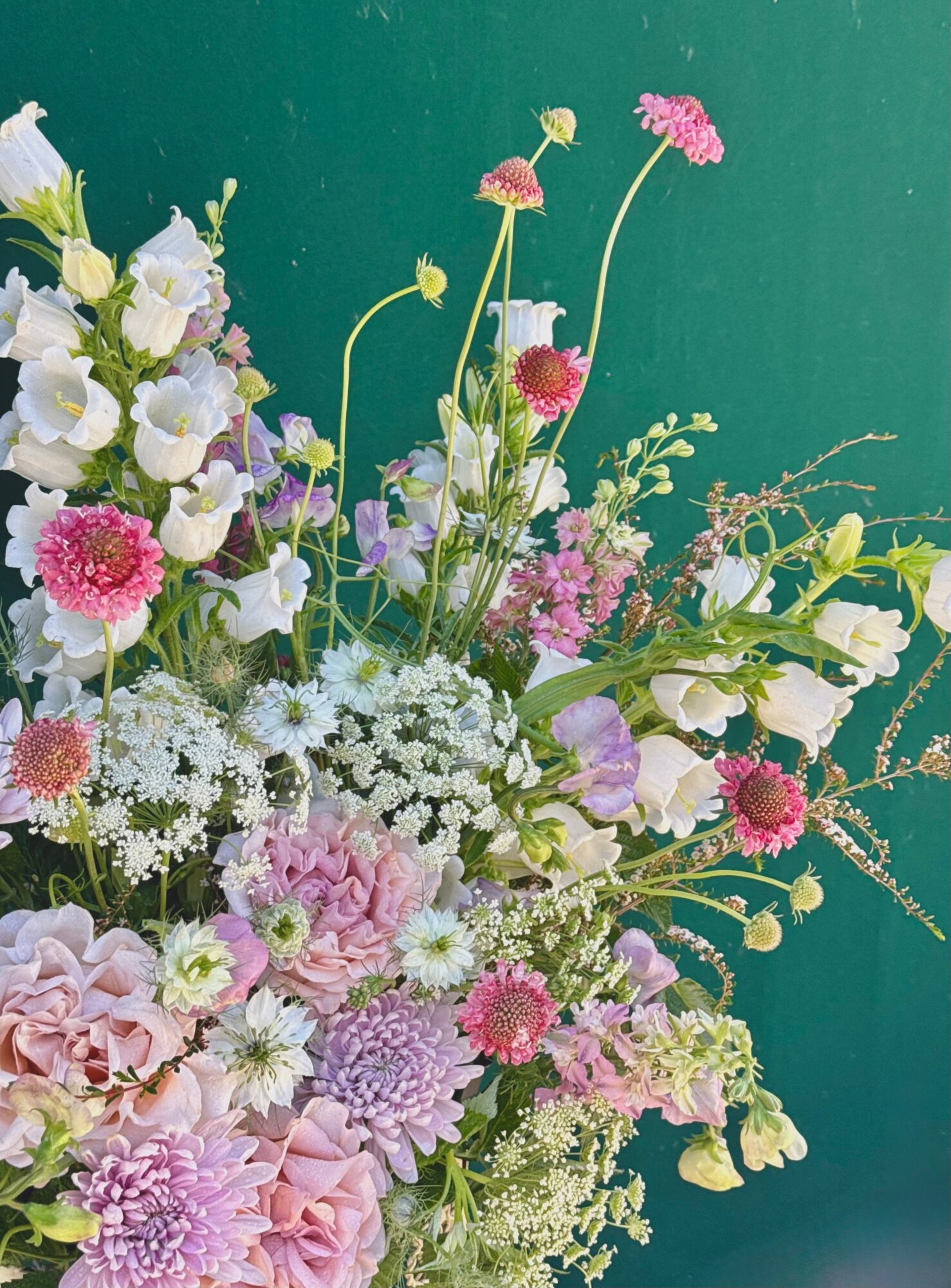 Arrangement of various pink, white, and purple flowers against a green background.