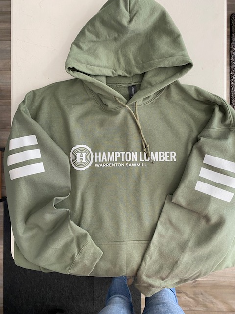 Green hoodie with white logo and three white stripes, hanging on a hook, with part of a person's arm visible.