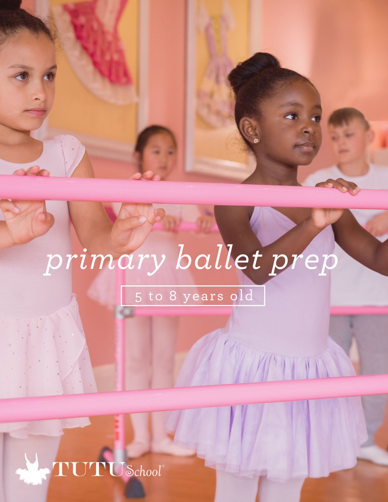 Two young girls in ballet tutus practicing at a barre in a dance studio, with other children in the background.