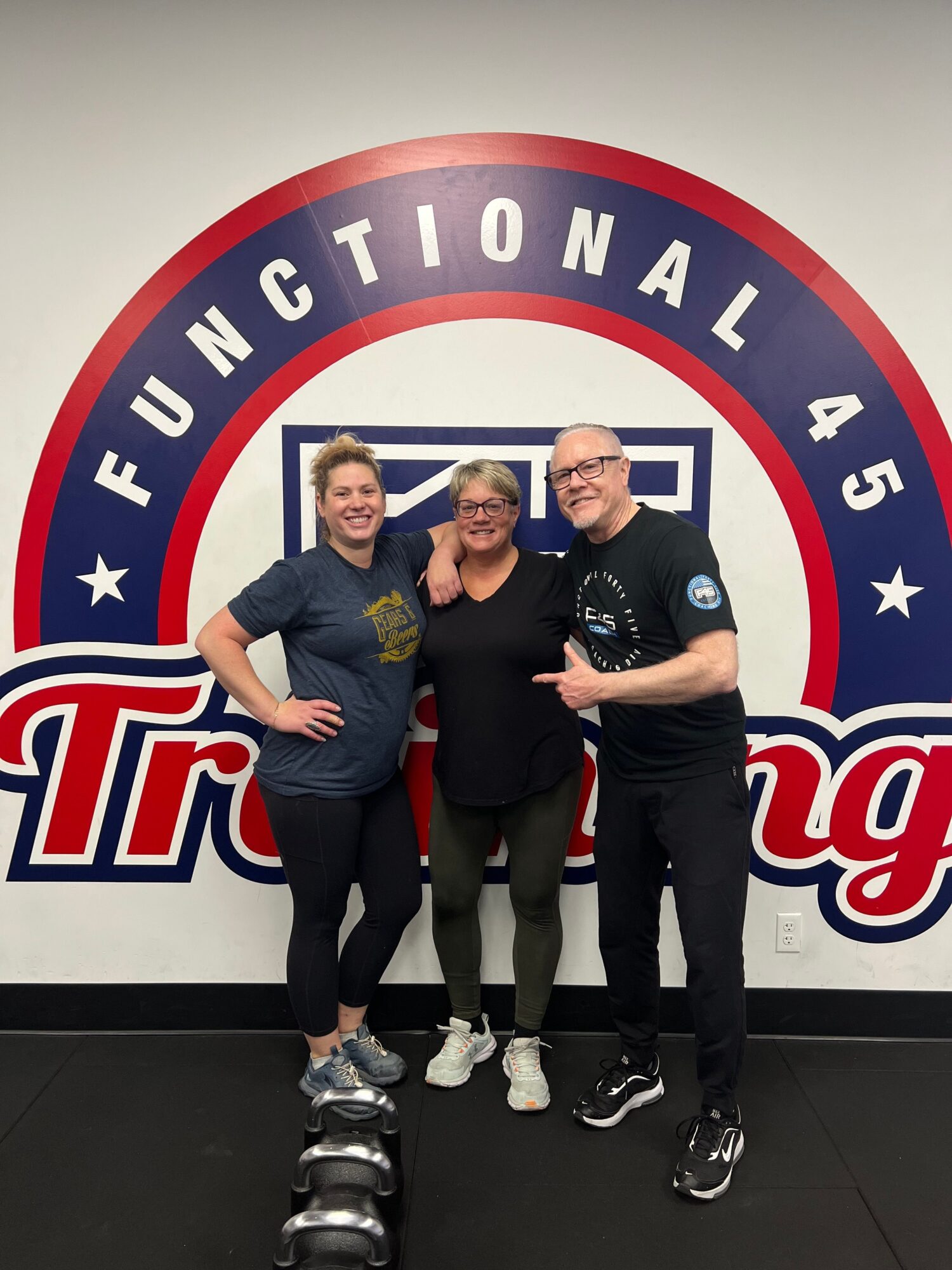 Three people standing in front of a circular sign with red, white, and blue colors, and text reading 'FUNDACIONAL 45'.