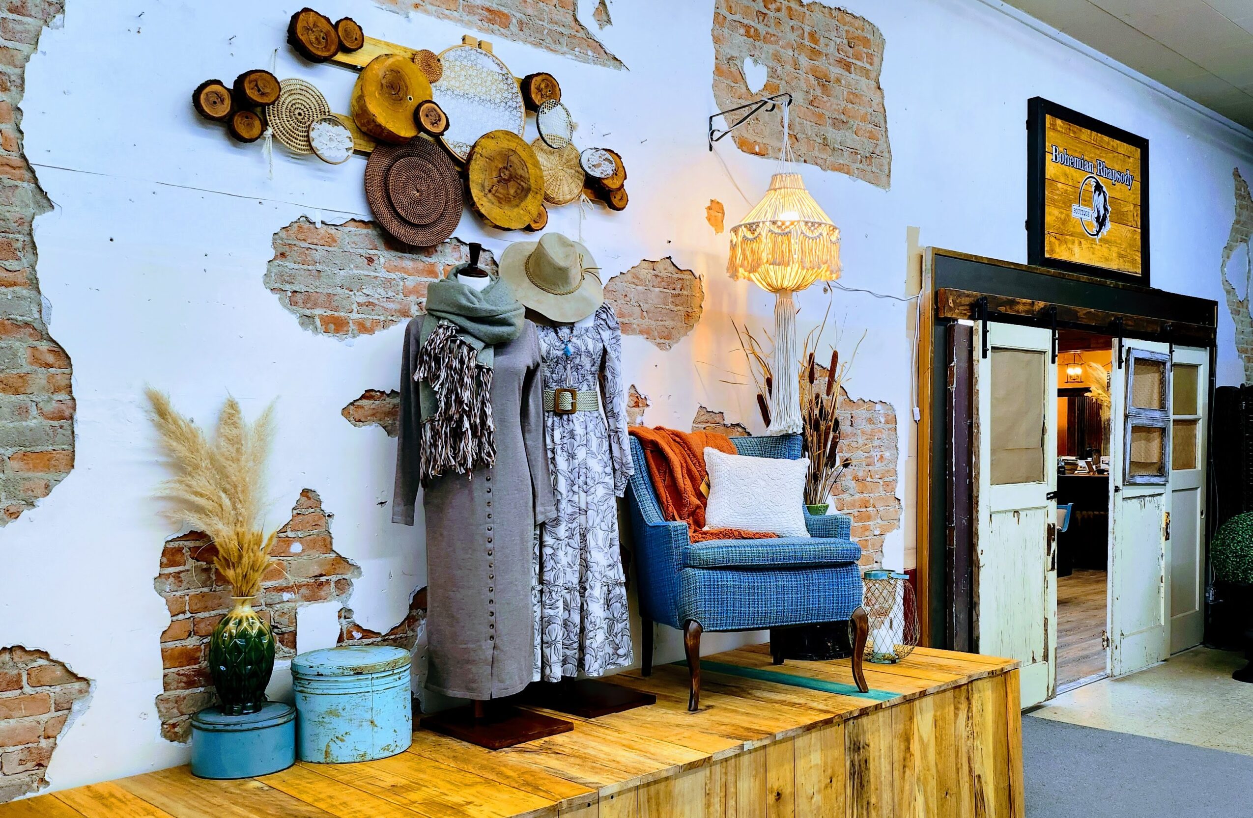 Decorative wall with hats, scarves, and wall art, blue armchair, and vintage cabinet in a cozy interior.