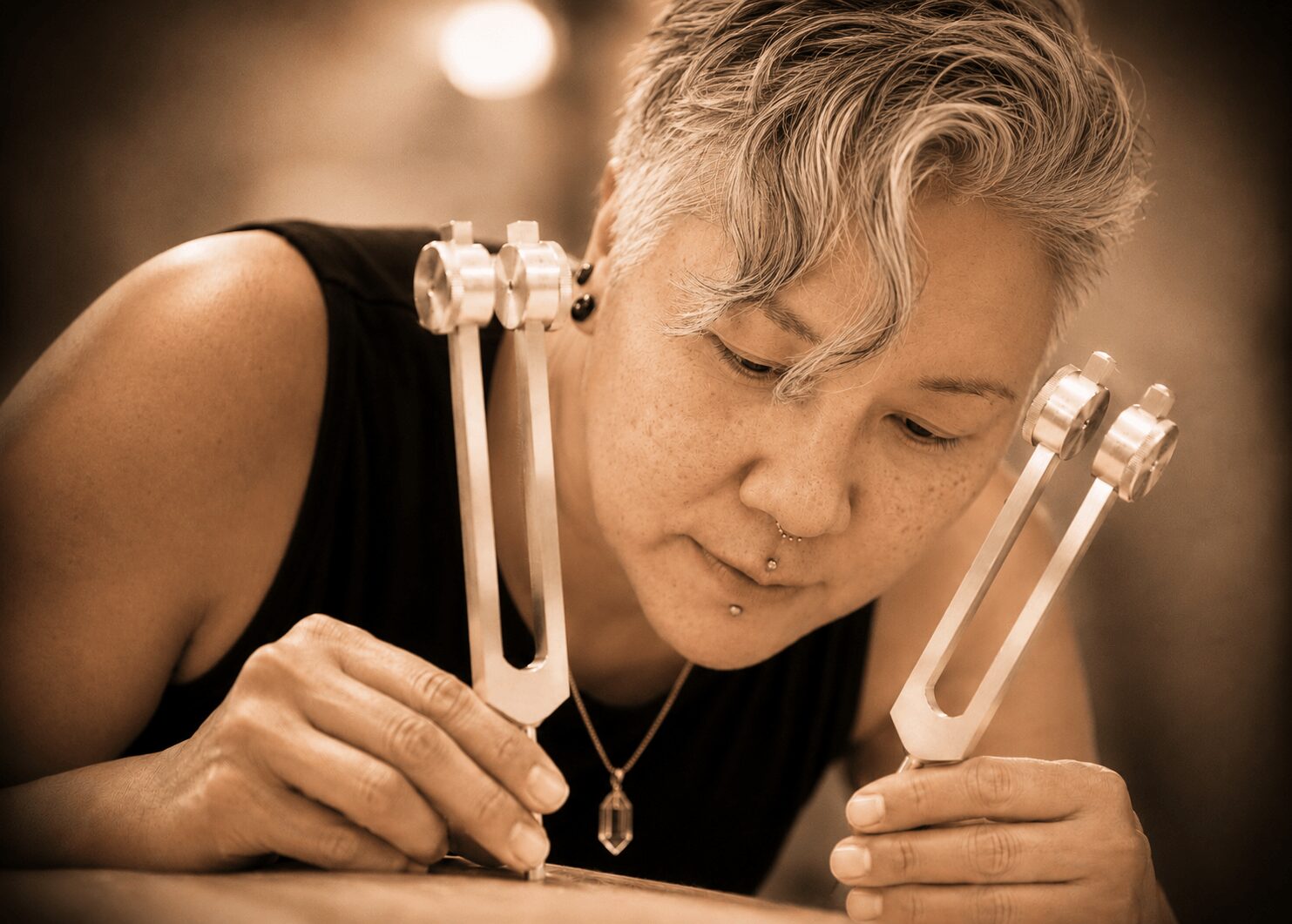 Person with short, wavy hair looks closely at a device with two long, U-shaped metal parts, holding it with both hands.