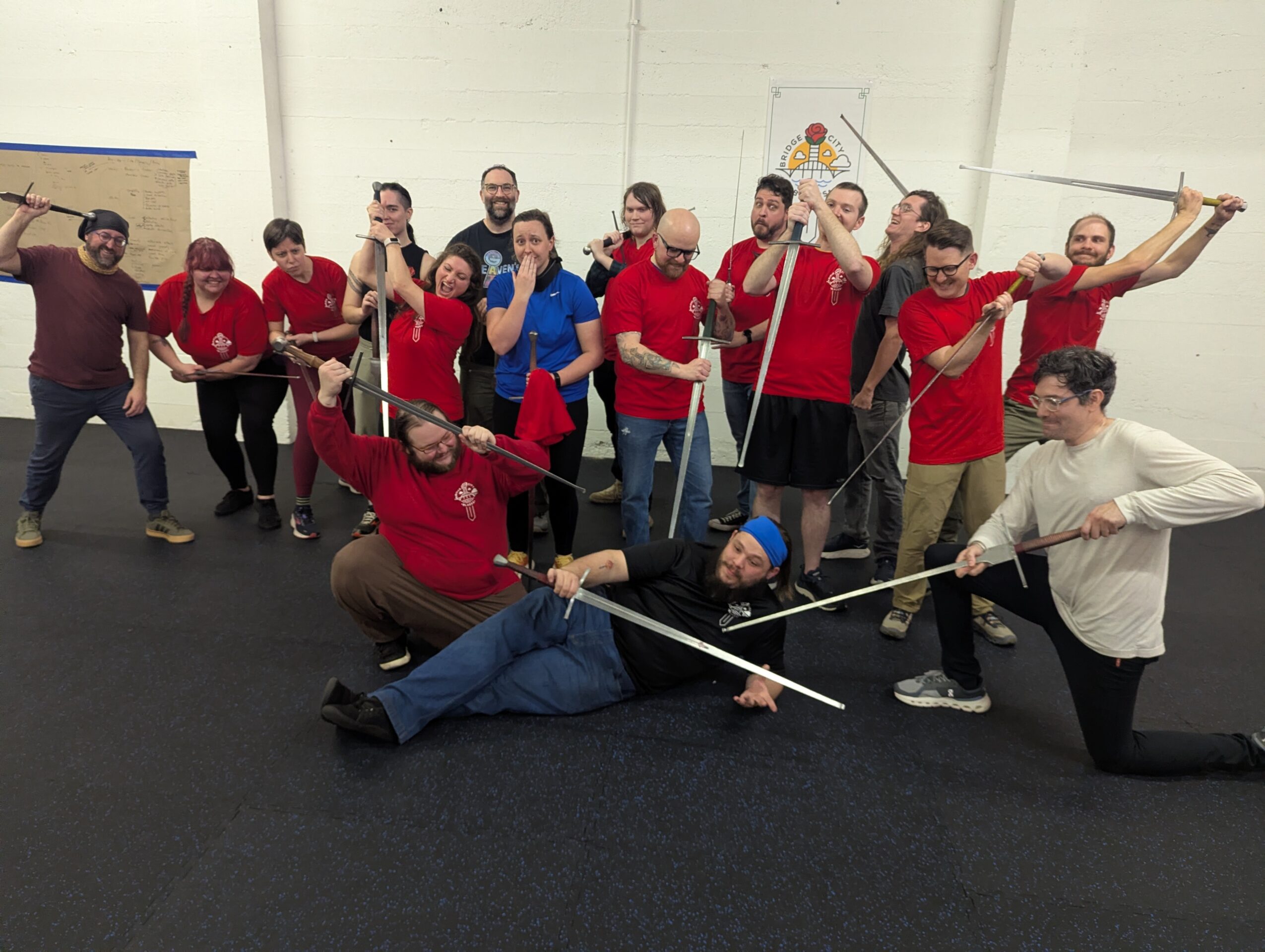 Group of people posing with ropes in a room, some pulling, some holding ropes, some lying on the floor, smiling.