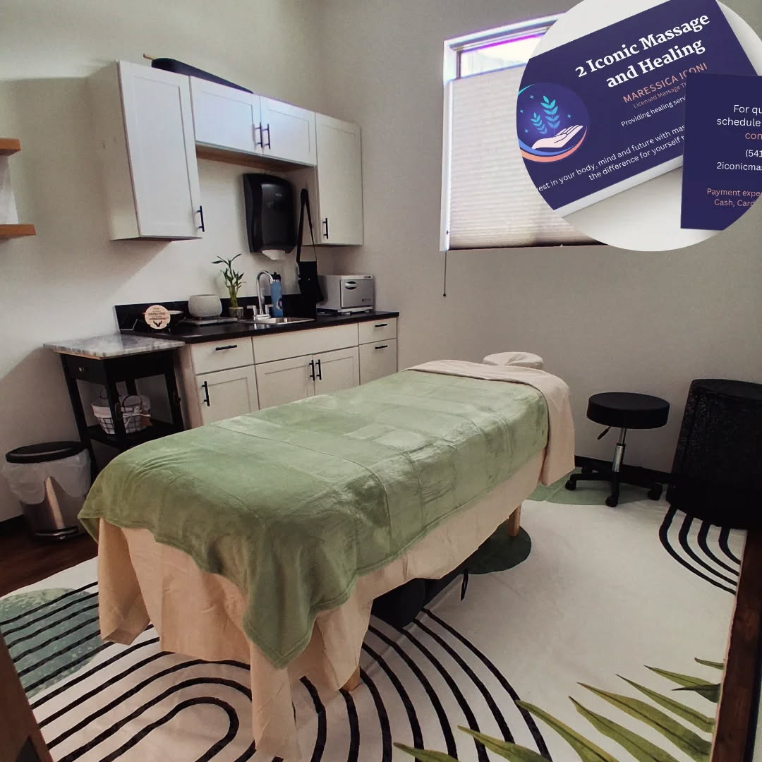 Massage table with green cover in a treatment room, shelves, window, and a sign about massage and healing, 20 words.