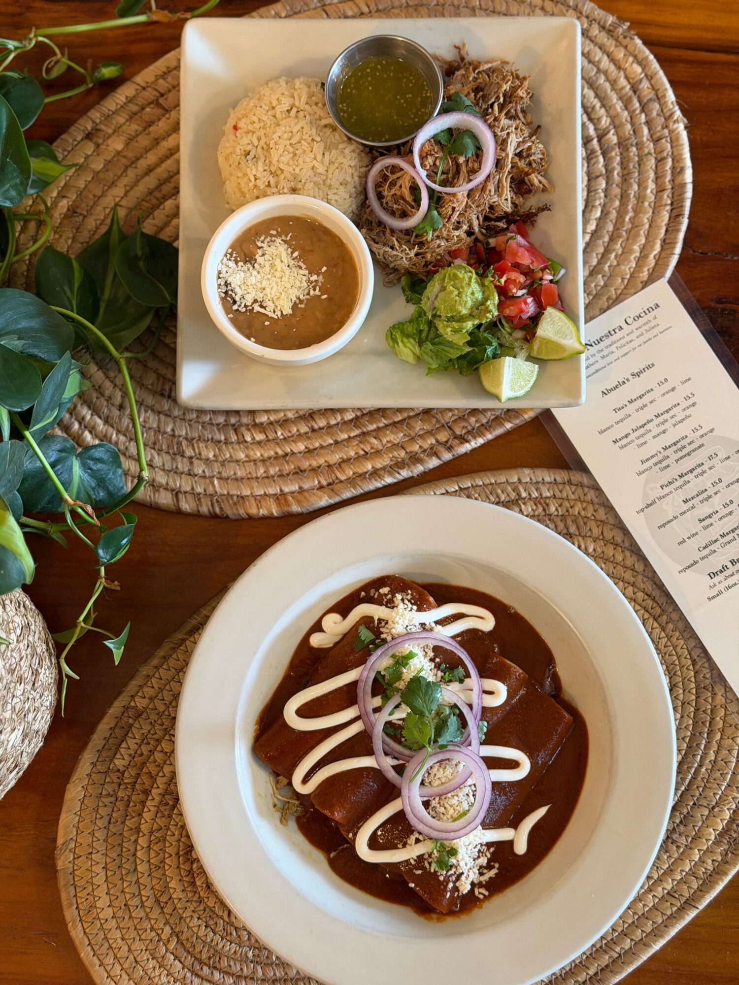 Square plate with rice, salad, and sauces, and a round bowl with a dish topped with sauce and onions, on a woven placemat.