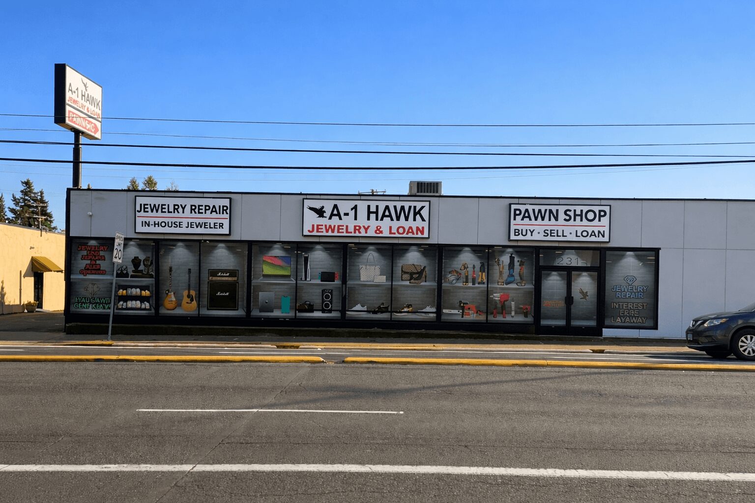 Storefront with signs for jewelry repair, pawn shop, and jewelry and loan services, with large windows and a parking lot in front.