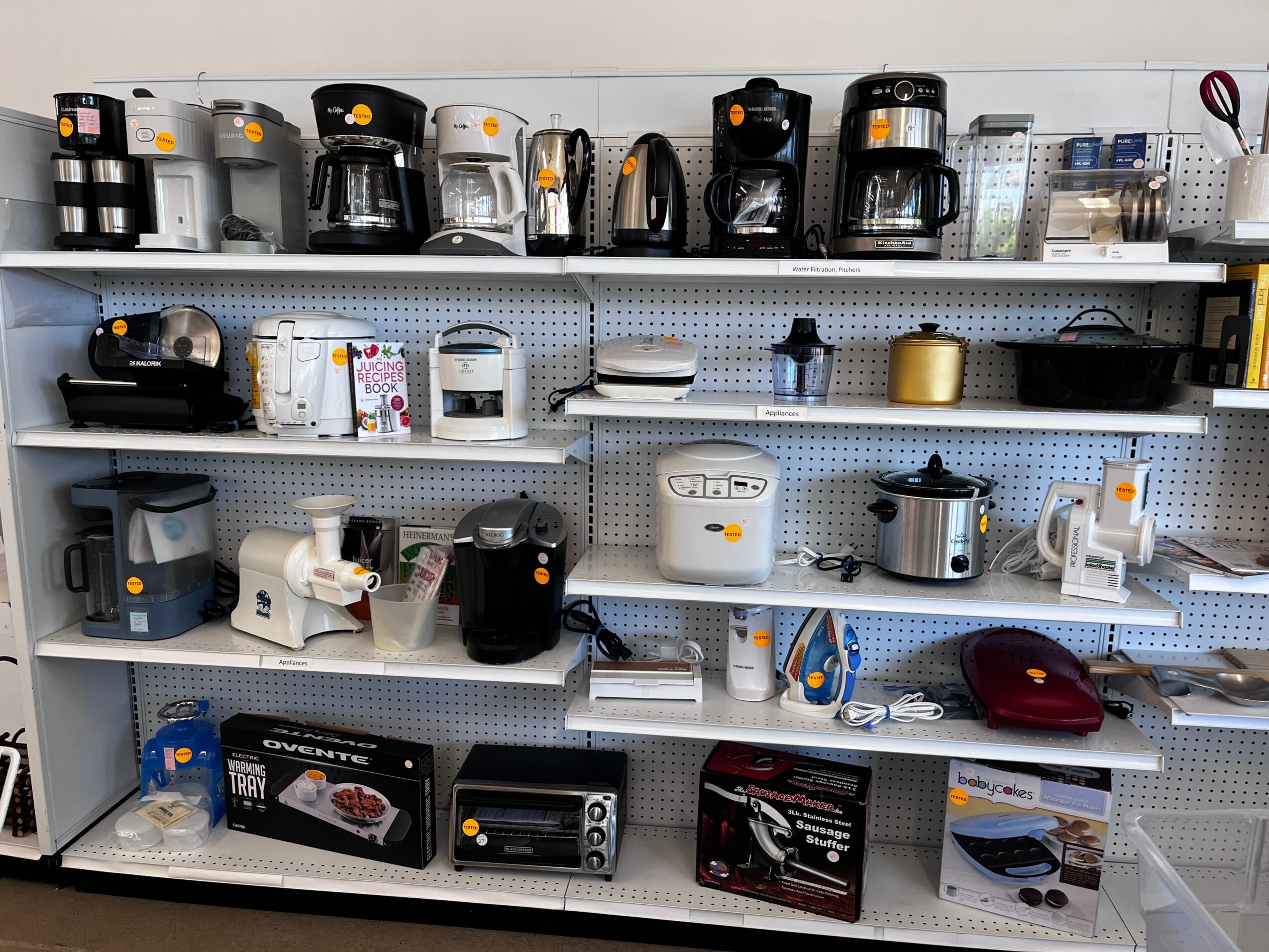 Coffee makers and kitchen appliances on shelves in a store display, with various models and colors visible.