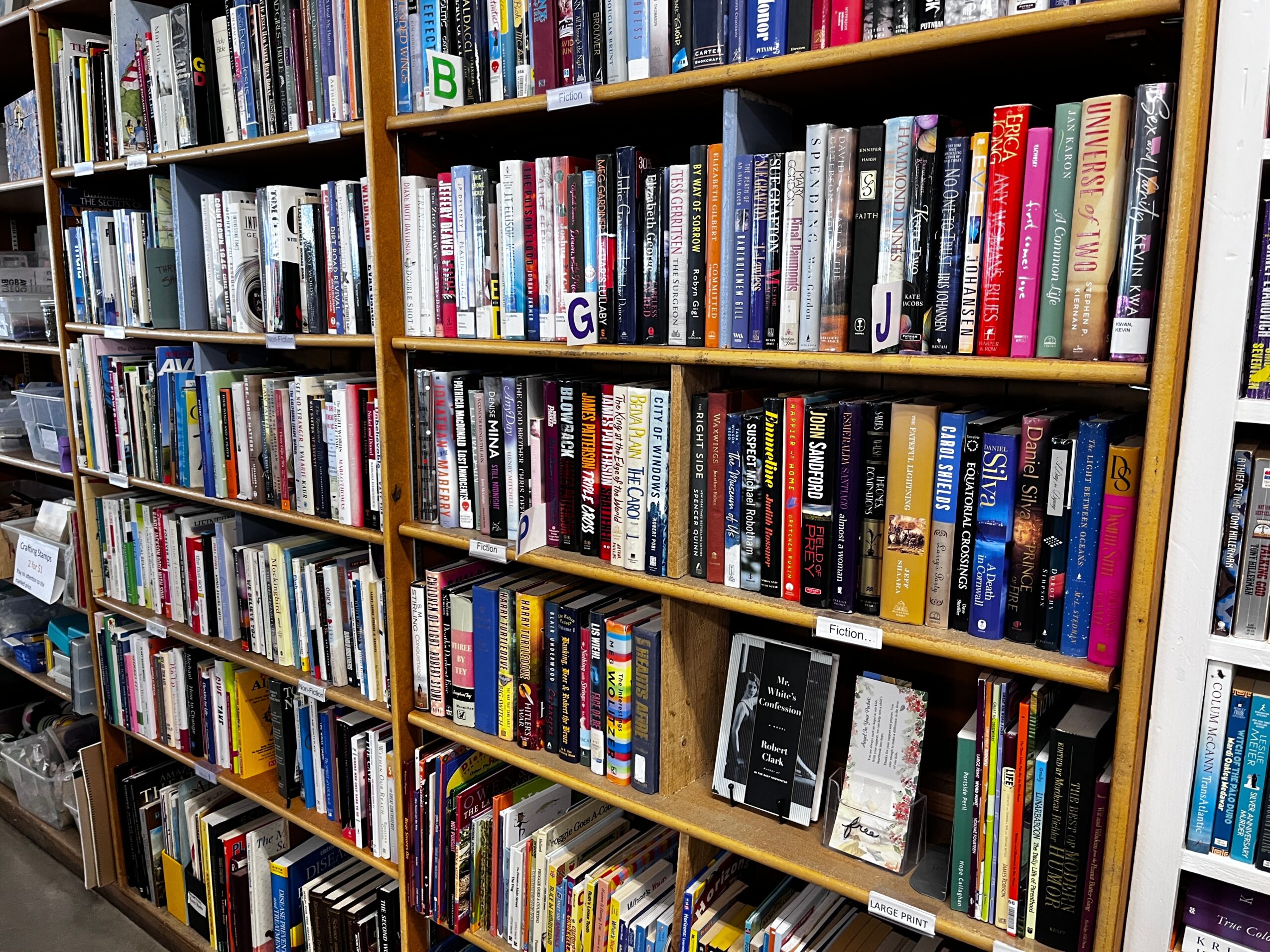 Bookshelves filled with books in a library or bookstore, organized on wooden shelves.