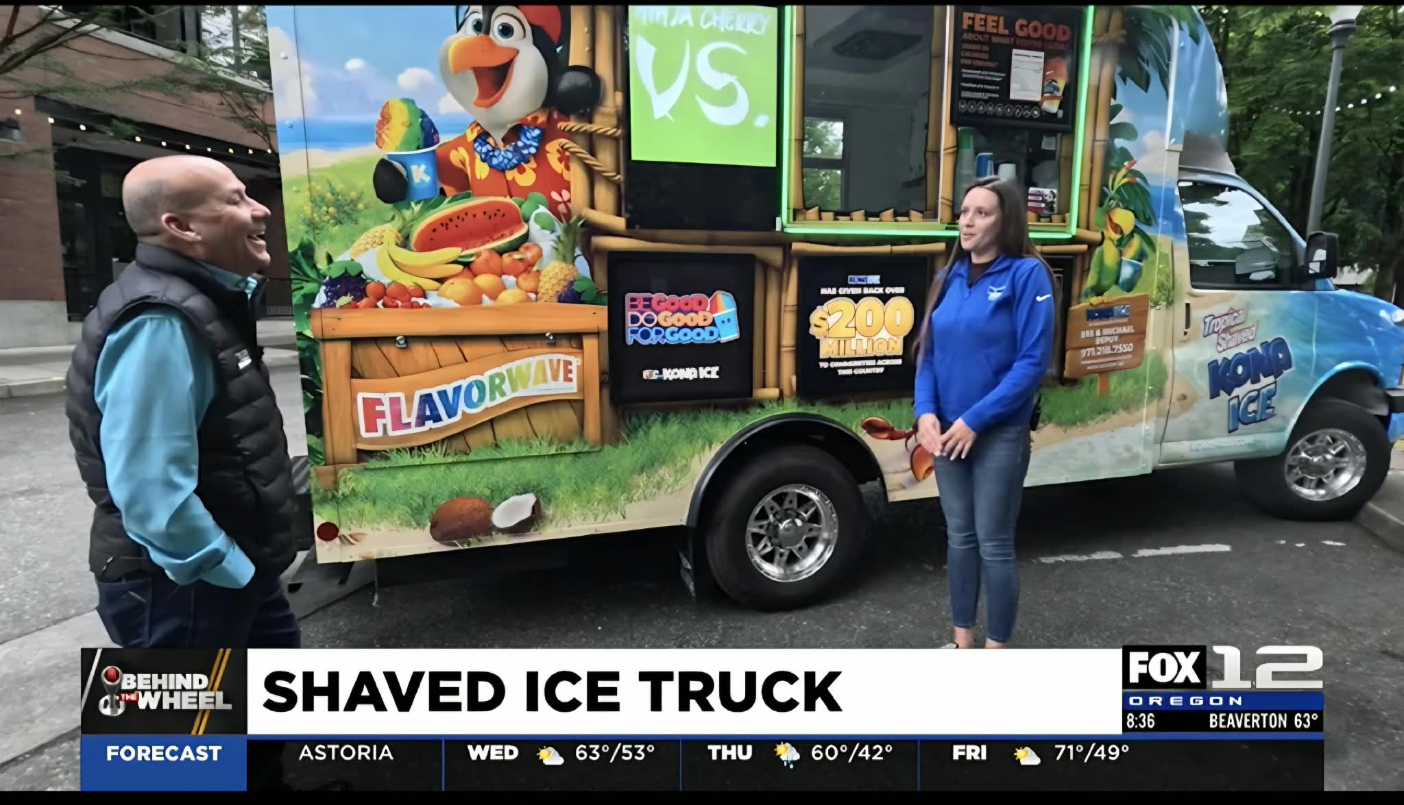 Two people stand in front of a colorful ice cream truck with cartoon characters, outdoors on a sunny day.