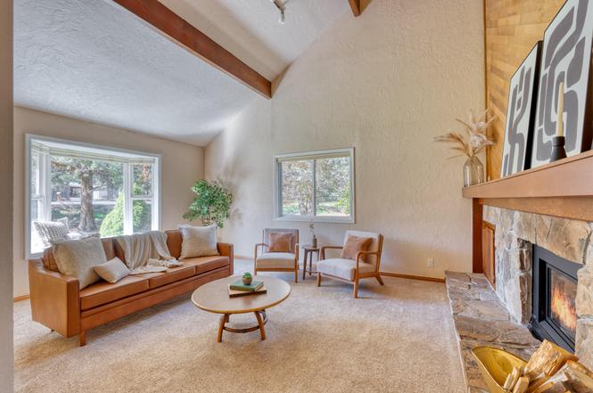 Living room with a sofa, two armchairs, a coffee table, fireplace, and large windows, bright and cozy atmosphere.
