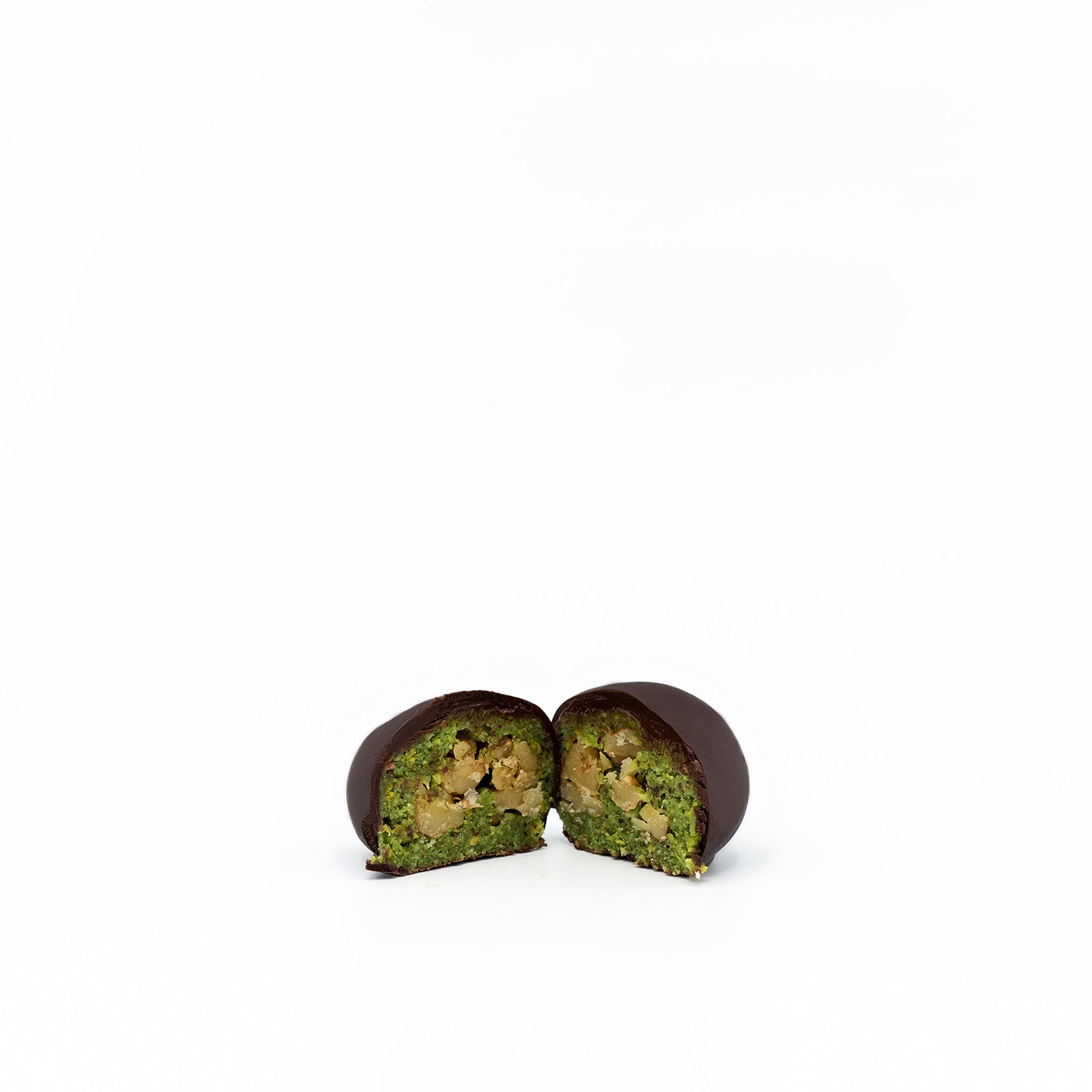 Chocolate-covered green cake with a filling, cut in half, on a white background.