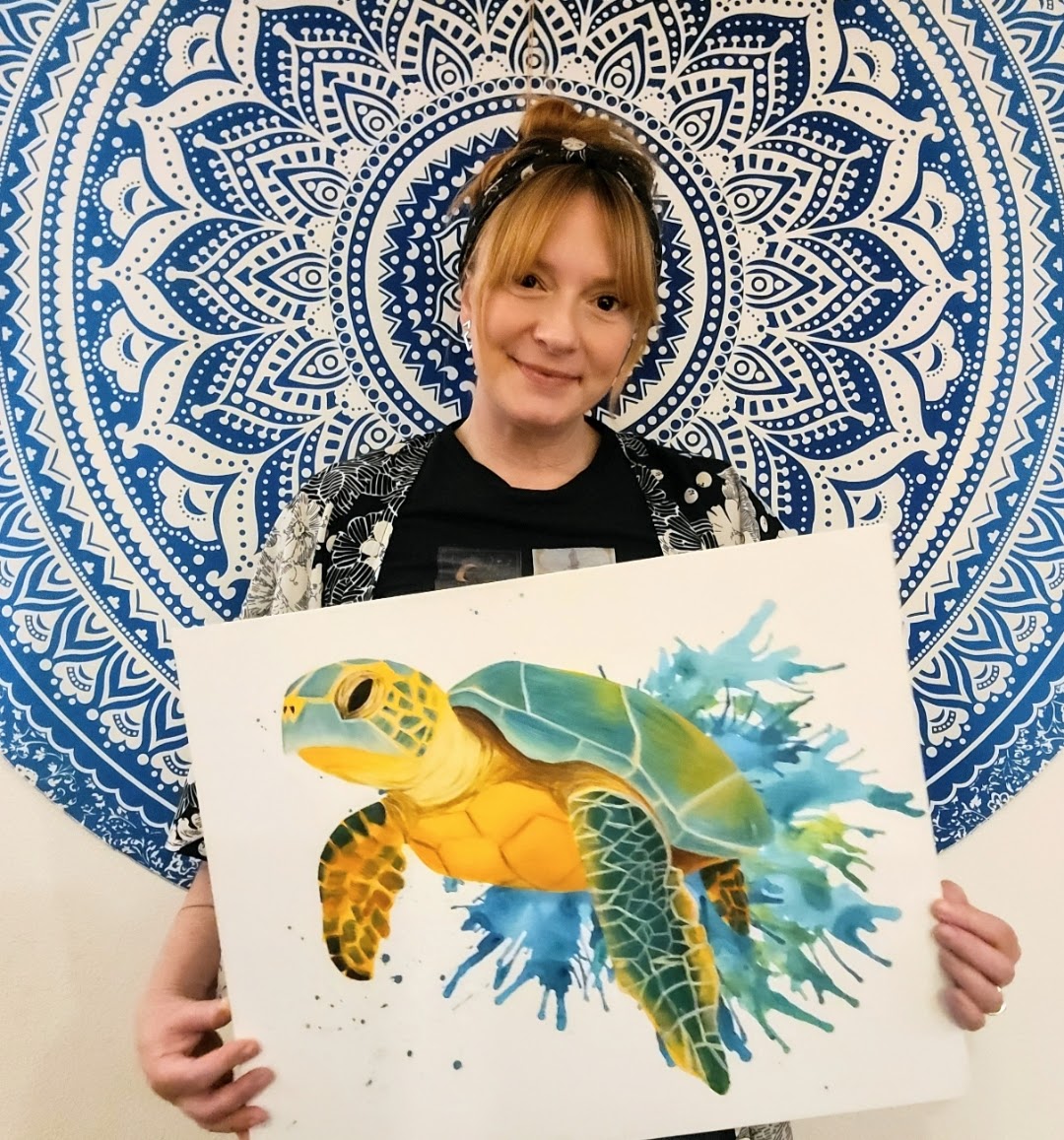 Person holding a colorful turtle illustration in front of a blue and white mandala background.