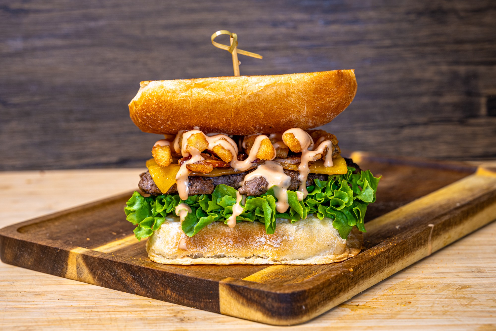 Sandwich with bread, lettuce, cheese, mushrooms, and other ingredients on a wooden board.