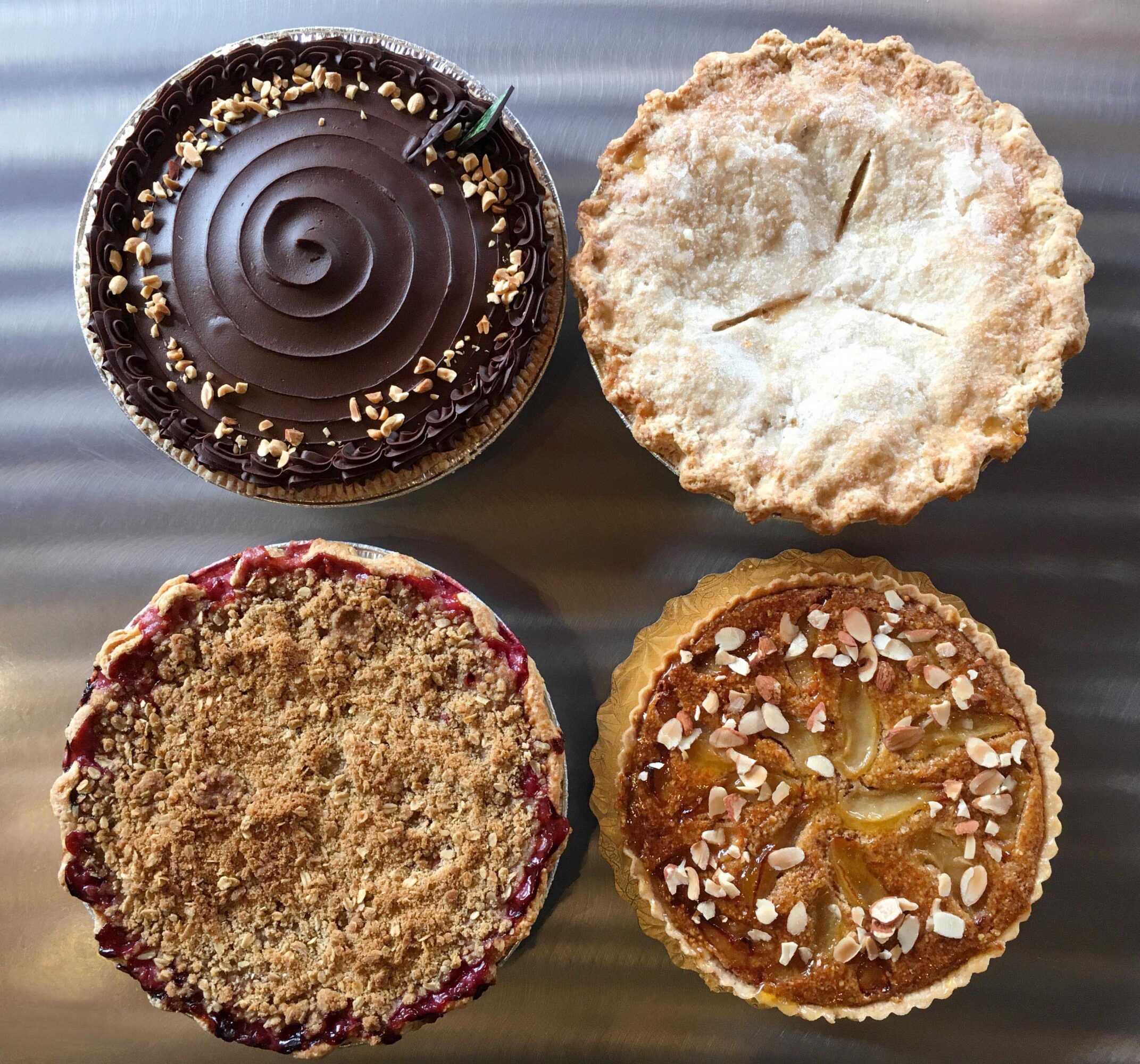 Four cupcakes with different toppings and textures, viewed from above on a wooden surface.