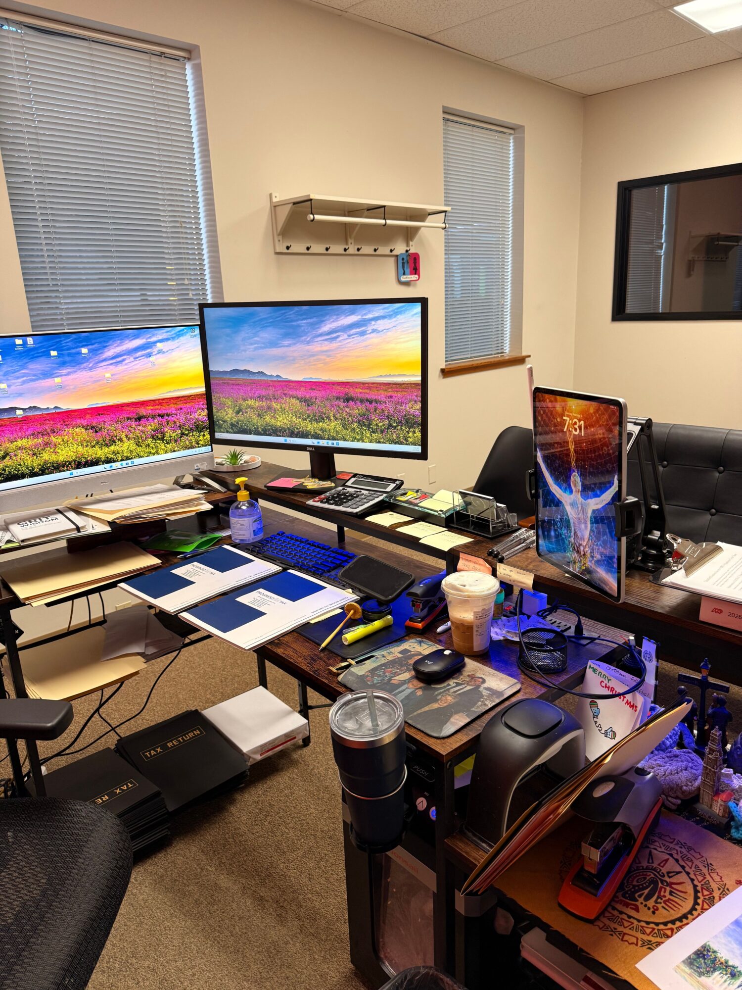 Cluttered desk with two monitors, a laptop, and various electronic devices and accessories.