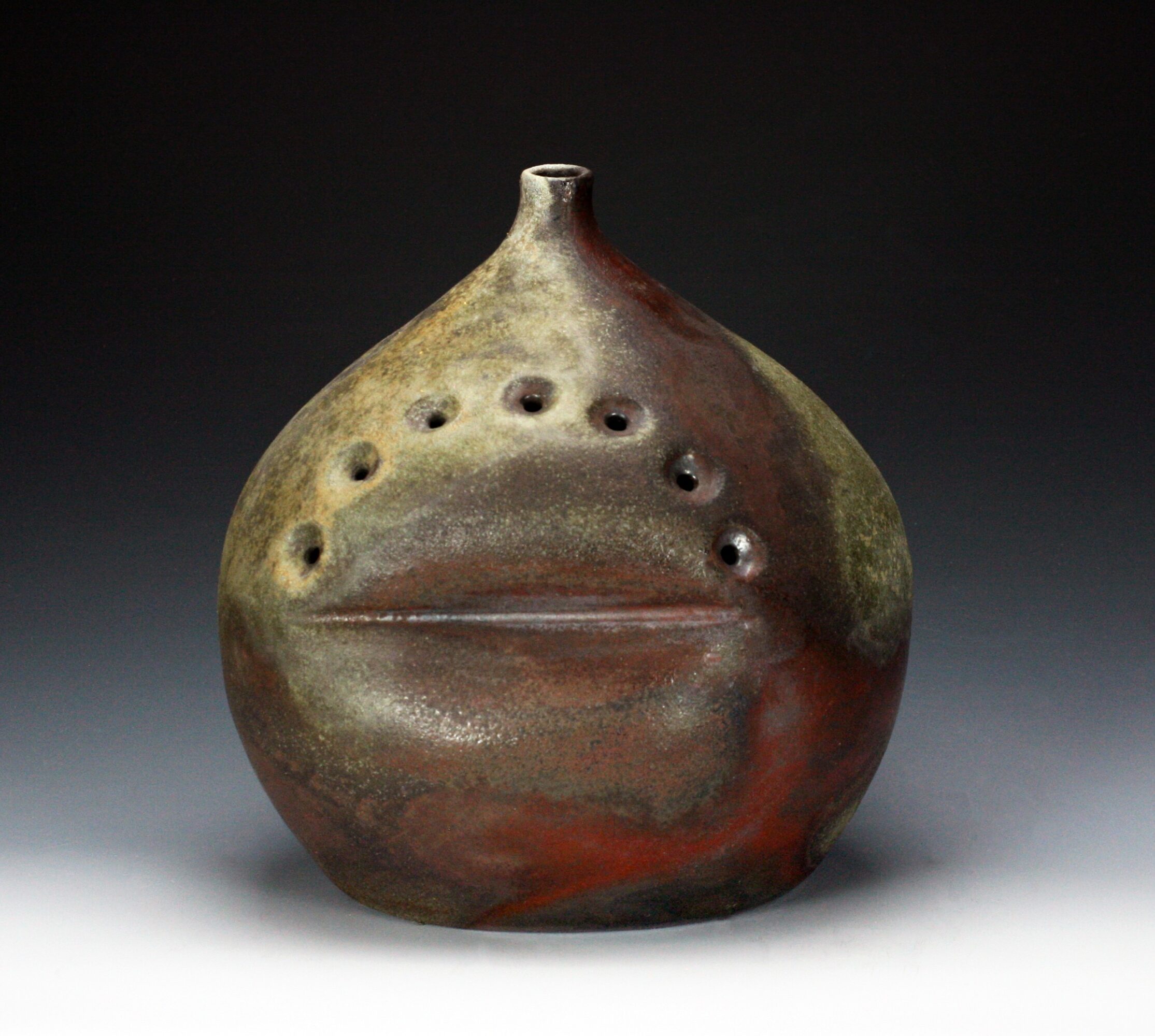 Round ceramic vessel with a narrow neck and decorative holes, earthy colors, on a gradient background.