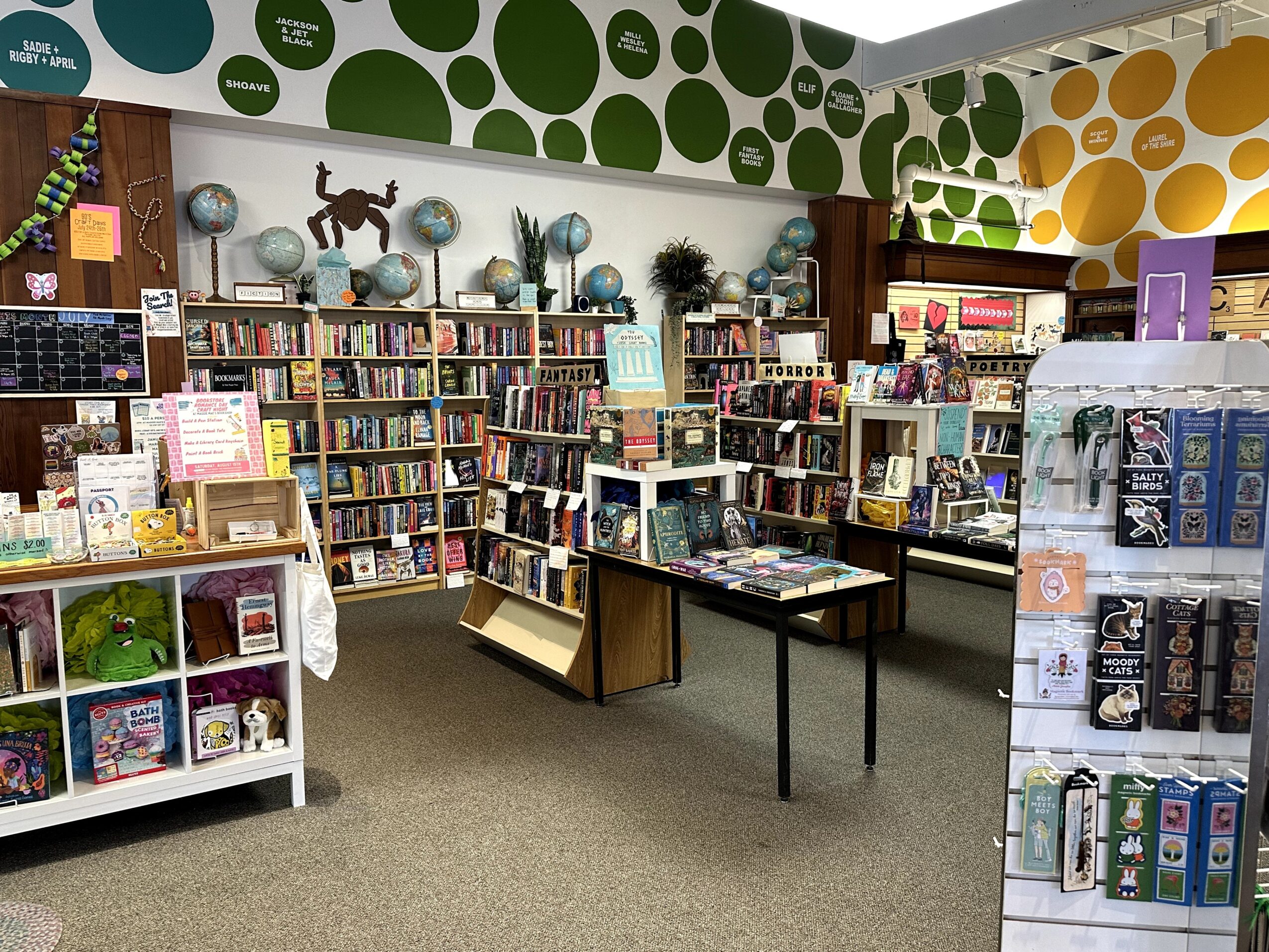Bookshelves filled with books in a store, with colorful wall patterns and display tables, no people visible.