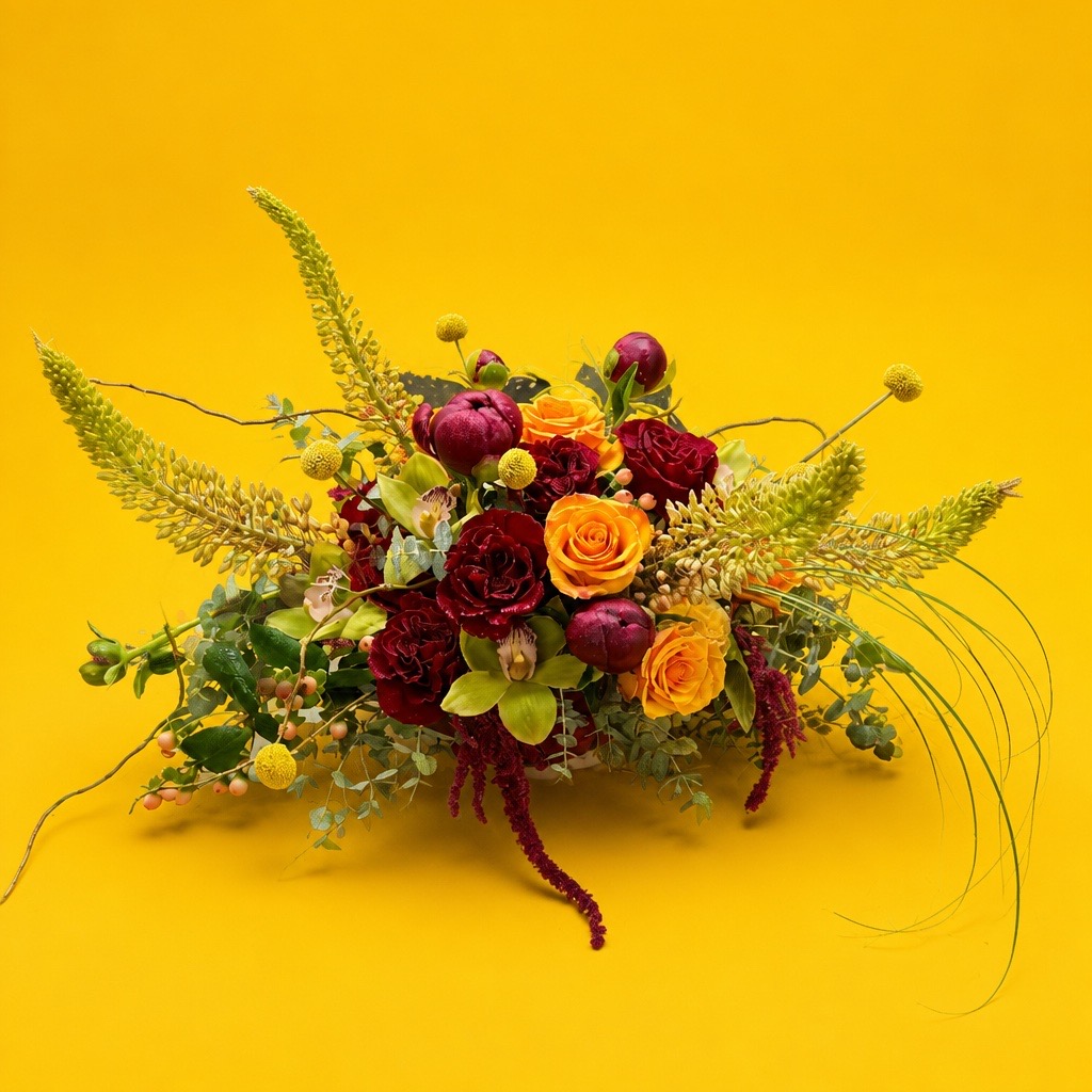 Flower arrangement with red and yellow flowers on a yellow background.
