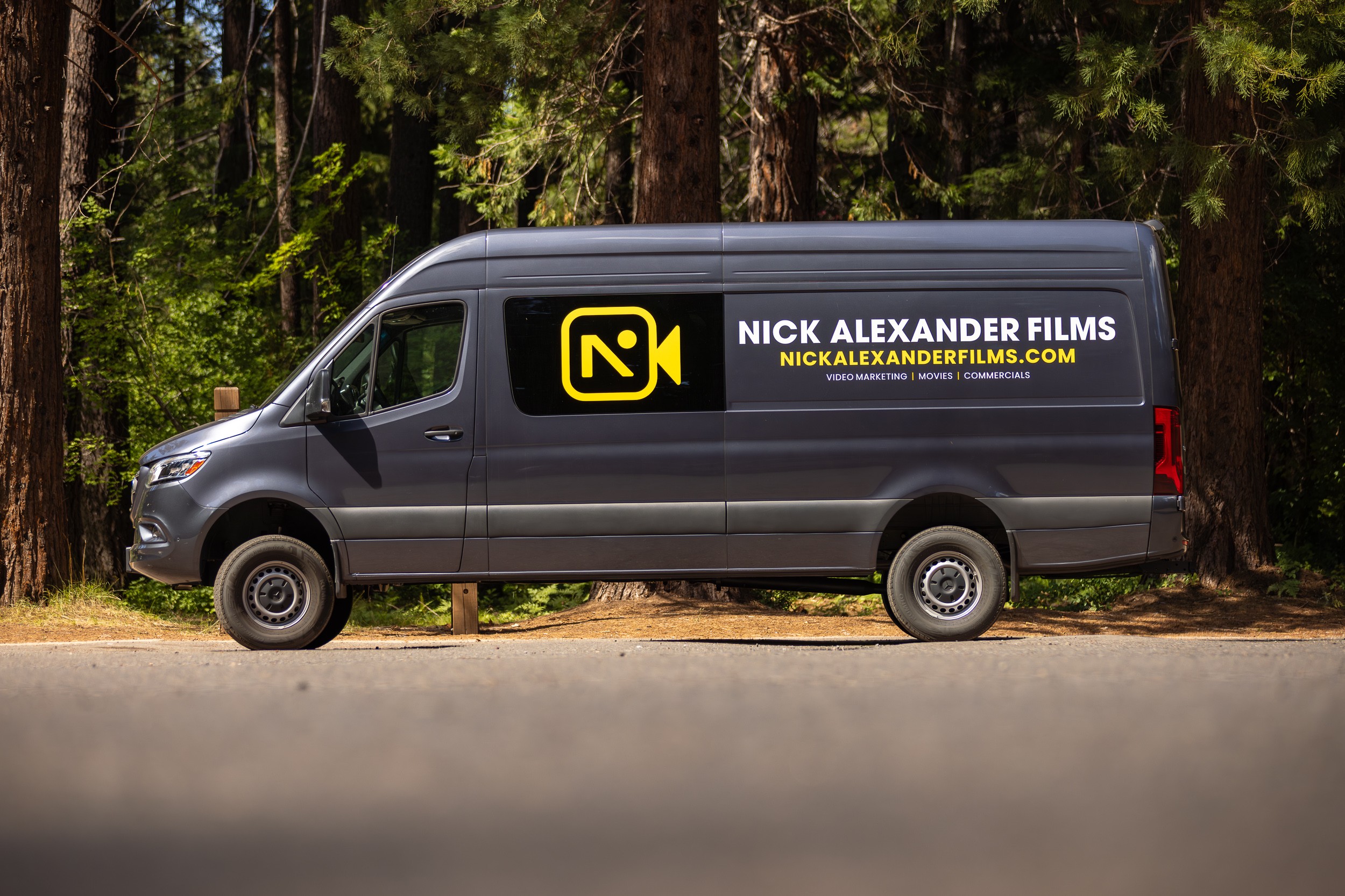 Gray van parked on a road with a forest background, displaying a logo and text for Nick Alexander Films.