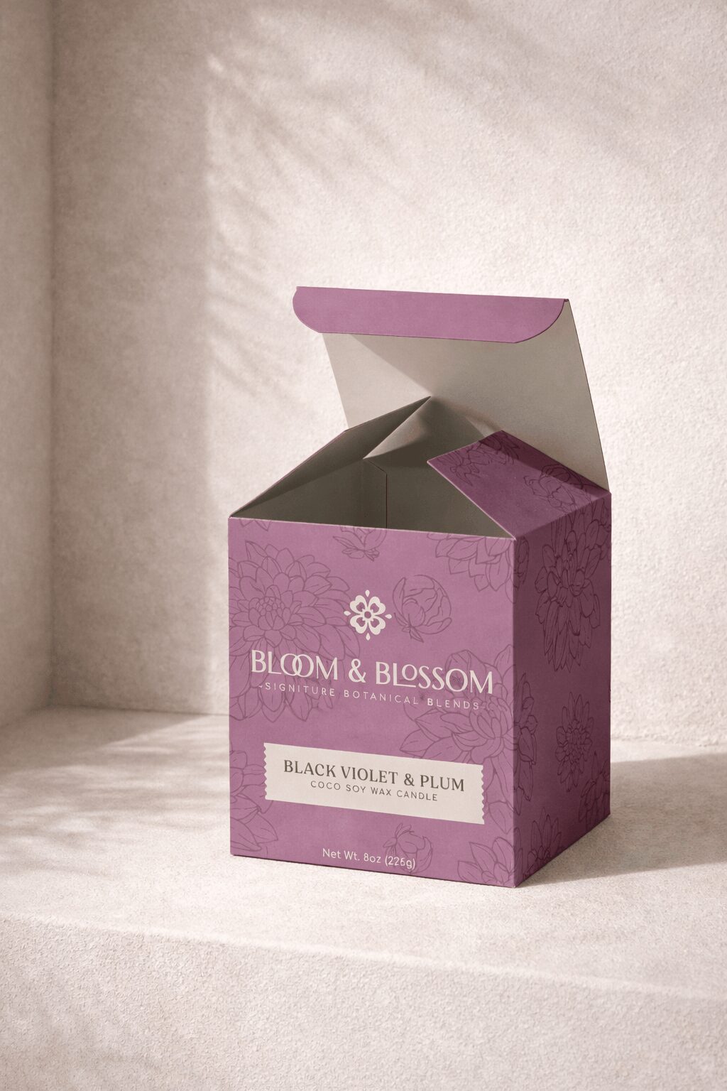 Open purple box with white label, partially revealing black violet and plum products inside, on a light surface with shadowed background.
