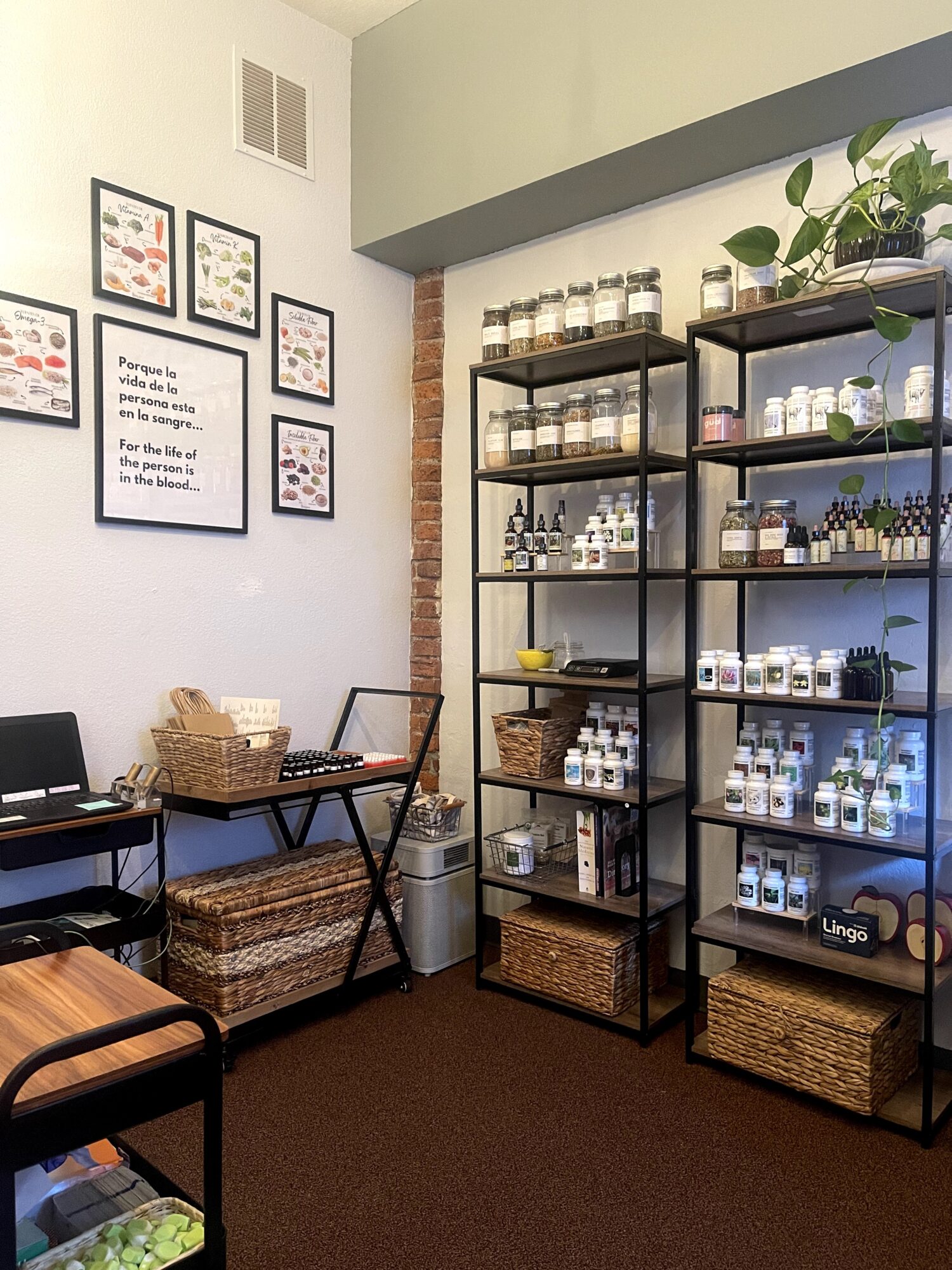 Interior of a room with shelves holding jars and bottles, framed pictures on the wall, and a small table with chairs.