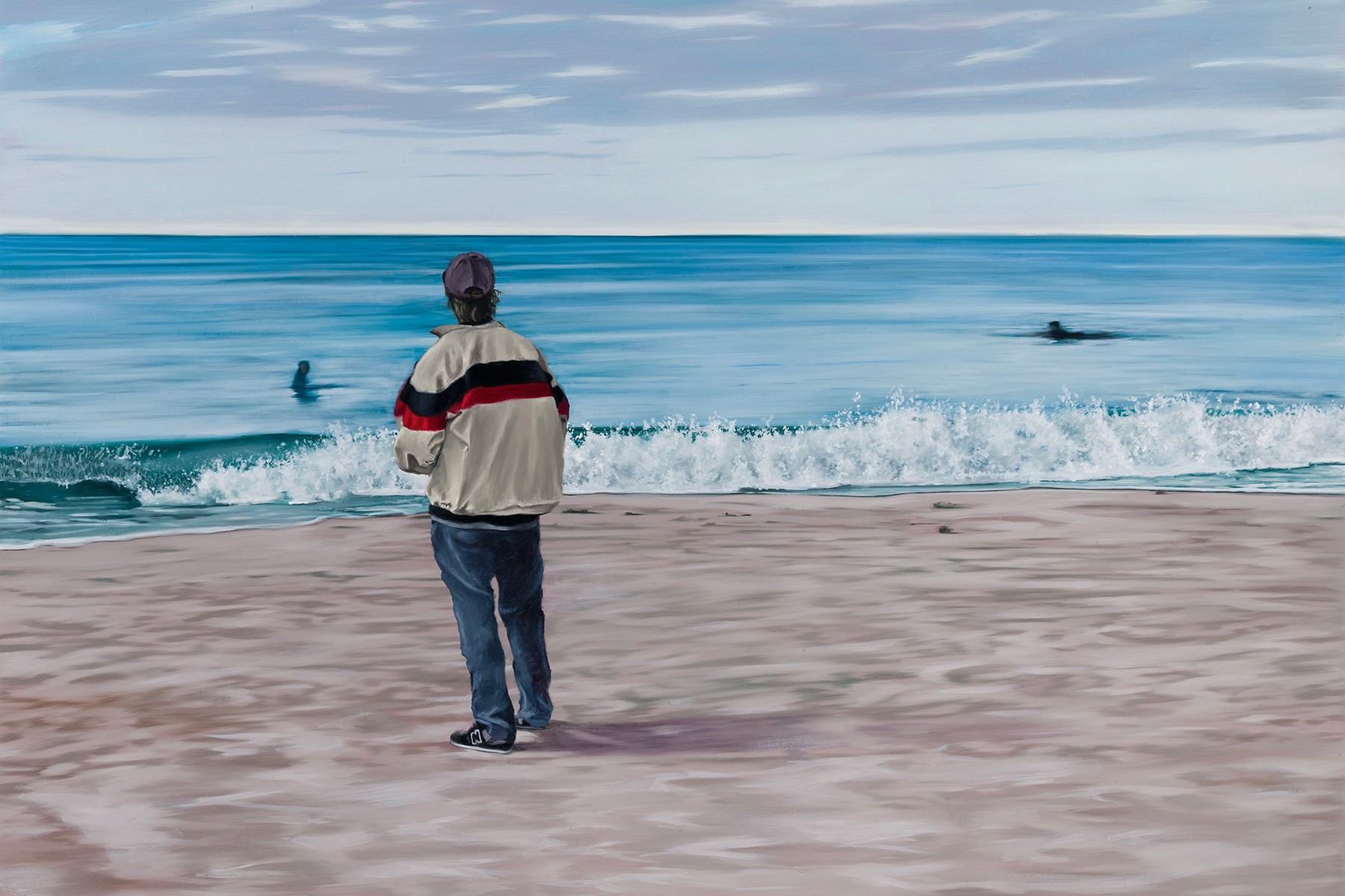 Person standing on beach watching the ocean, with a boat and a swimmer in the water, cloudy sky above.