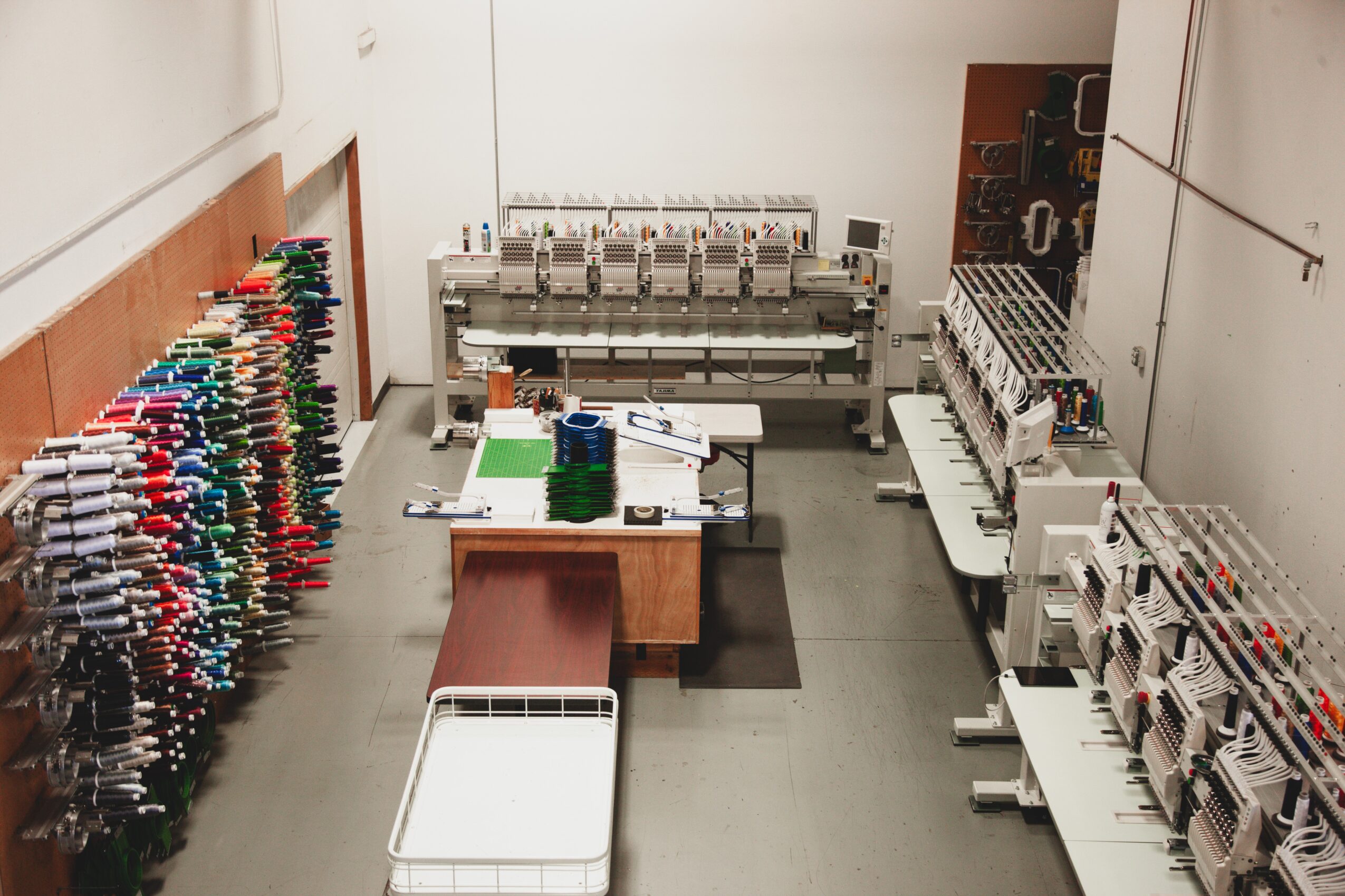 Workshop with shelves of colorful tools, a table with equipment, and organized machinery, viewed from above.