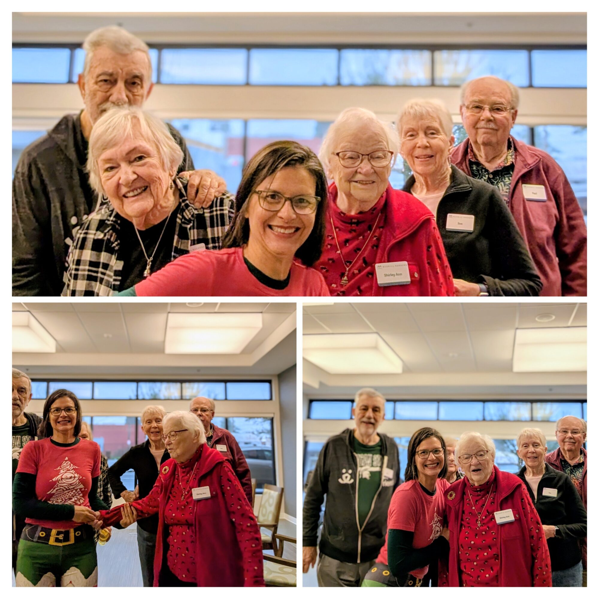 Group of elderly and younger people smiling indoors, some wearing name tags, in a well-lit room with large windows.