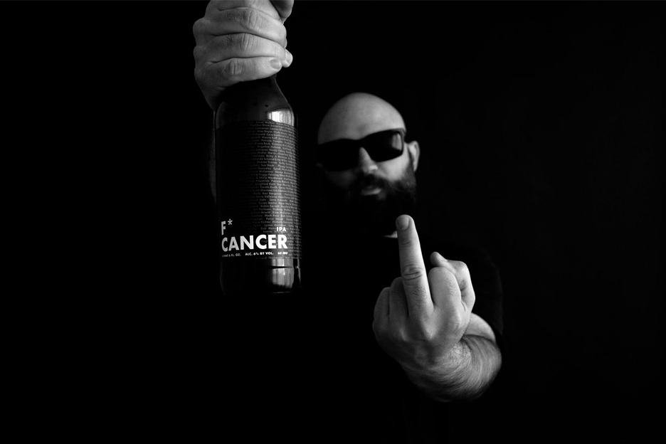 Person with sunglasses holding a bottle and showing middle finger, in black and white.