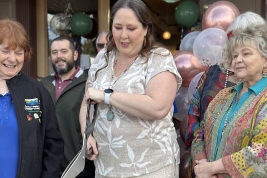 Group of four women and one man at a celebration with balloons in the background.