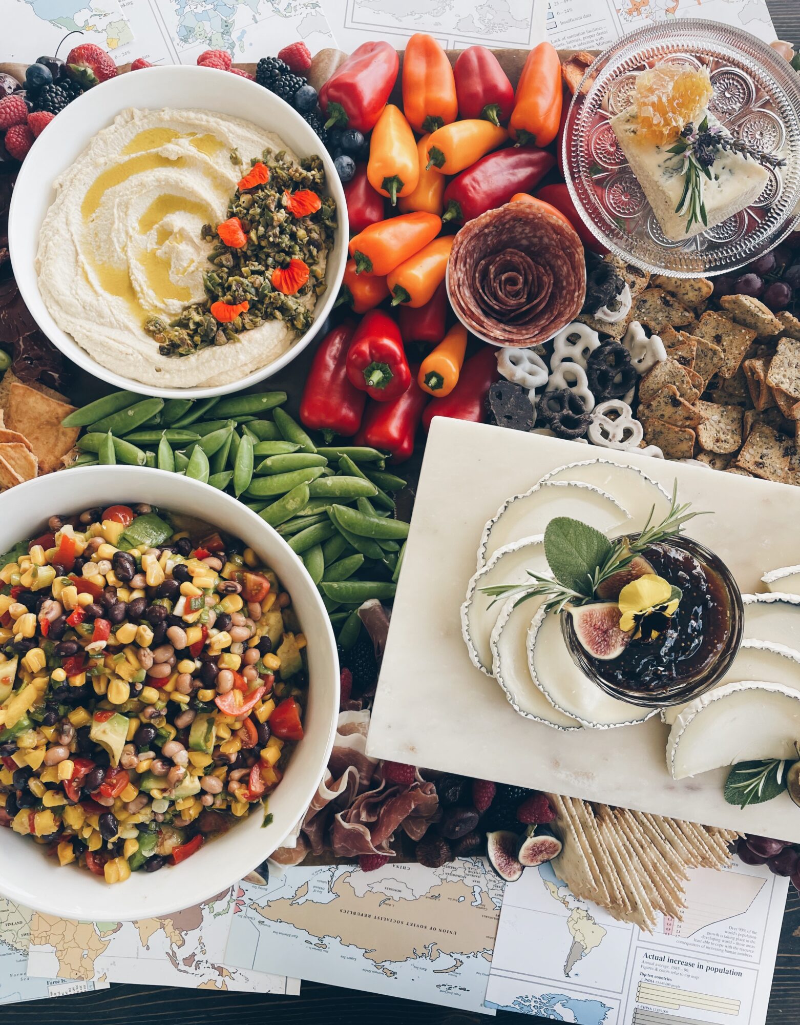 Assorted fruits, salads, and desserts on a table, including a bowl of salad, a bowl of grain salad, and a dessert with whipped cream and fruit.