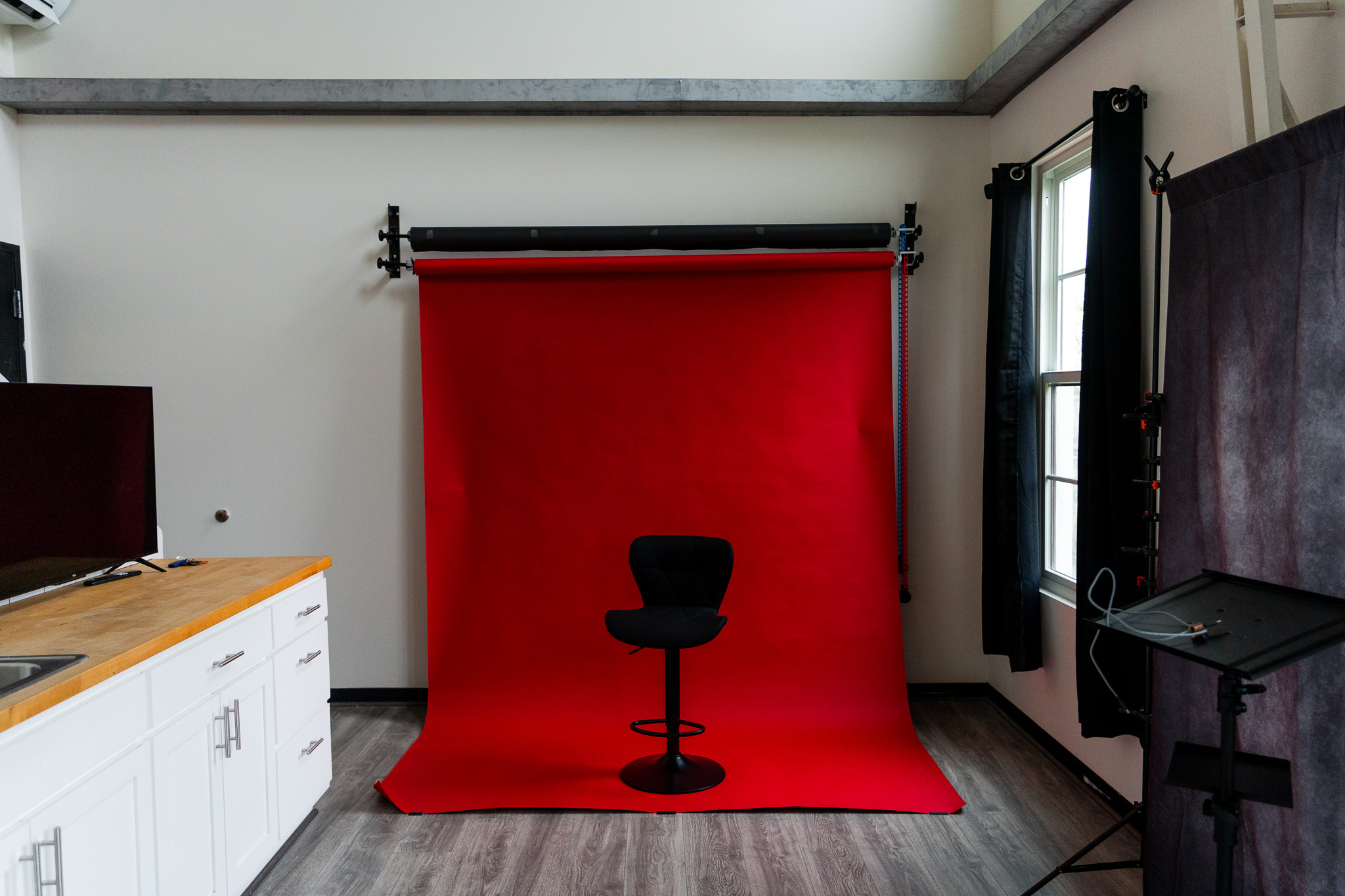 Red backdrop with a black office chair silhouette, set in a room with white walls, windows, and furniture.