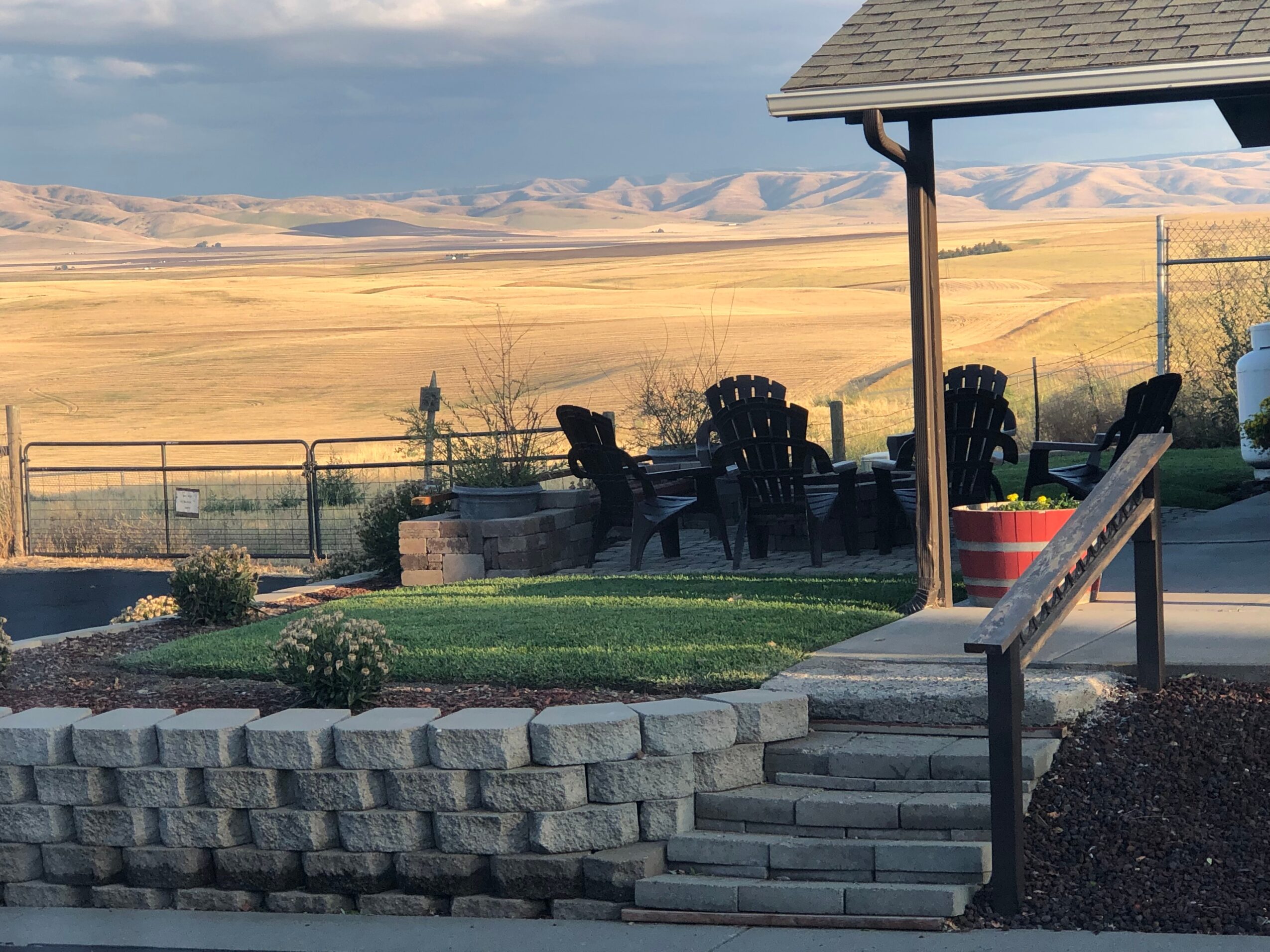 Patio area with chairs and a small table overlooking a vast open landscape with hills in the distance.