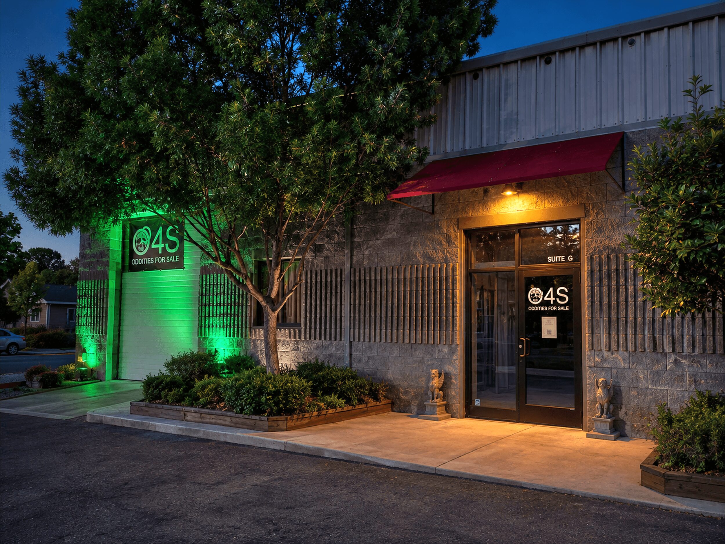 Building entrance with glass door, red awning, trees, and exterior lighting at dusk.