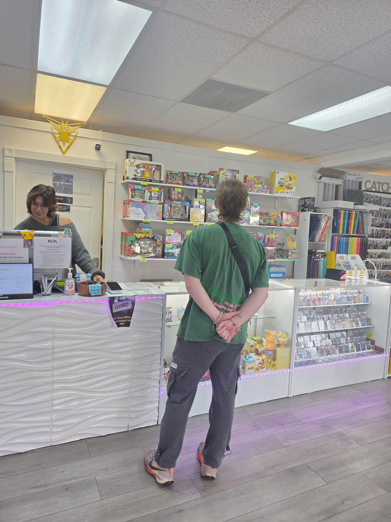 Person with green shirt browsing books in a store, shelves filled with colorful books behind them.