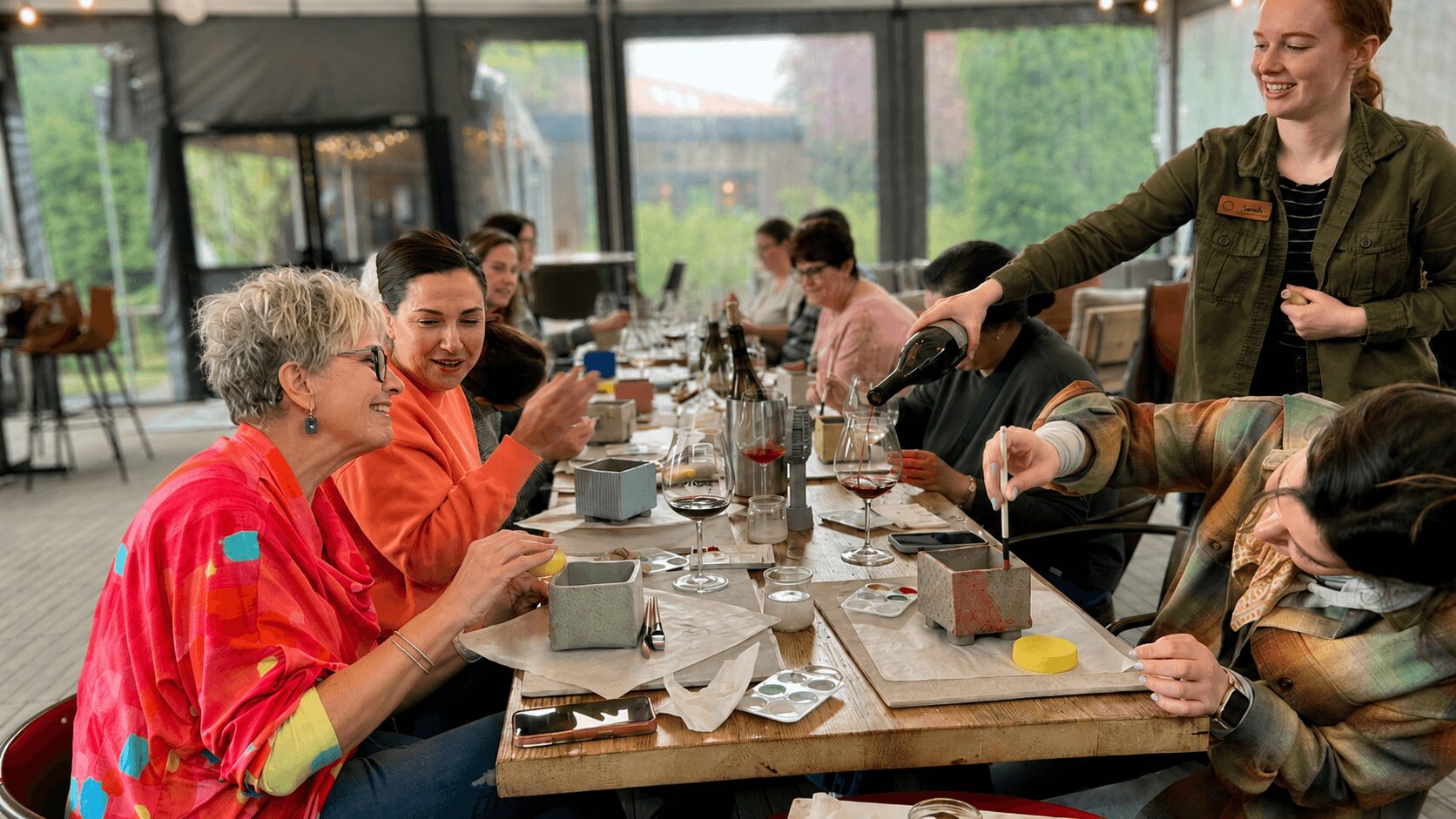 Group of people sitting at a long table in a bright room, enjoying a meal and conversation.