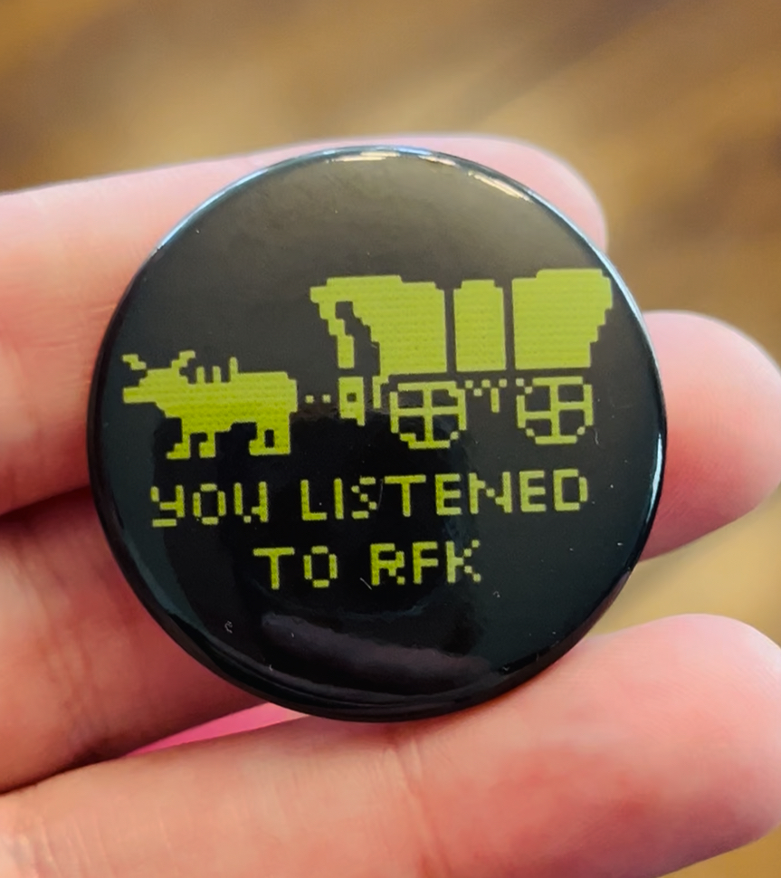 Digital display with pixelated dinosaur and spaceship, text reads 'YOU LISTENED TO RFK', black background, green graphics.