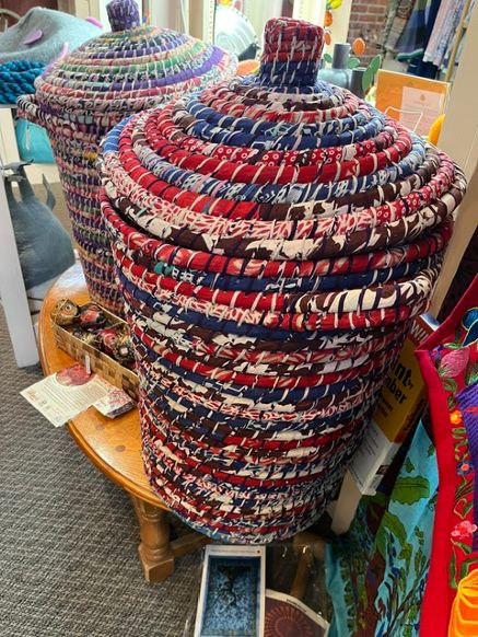 Stacked colorful woven hats on a wooden table, with various items and a colorful background behind them.