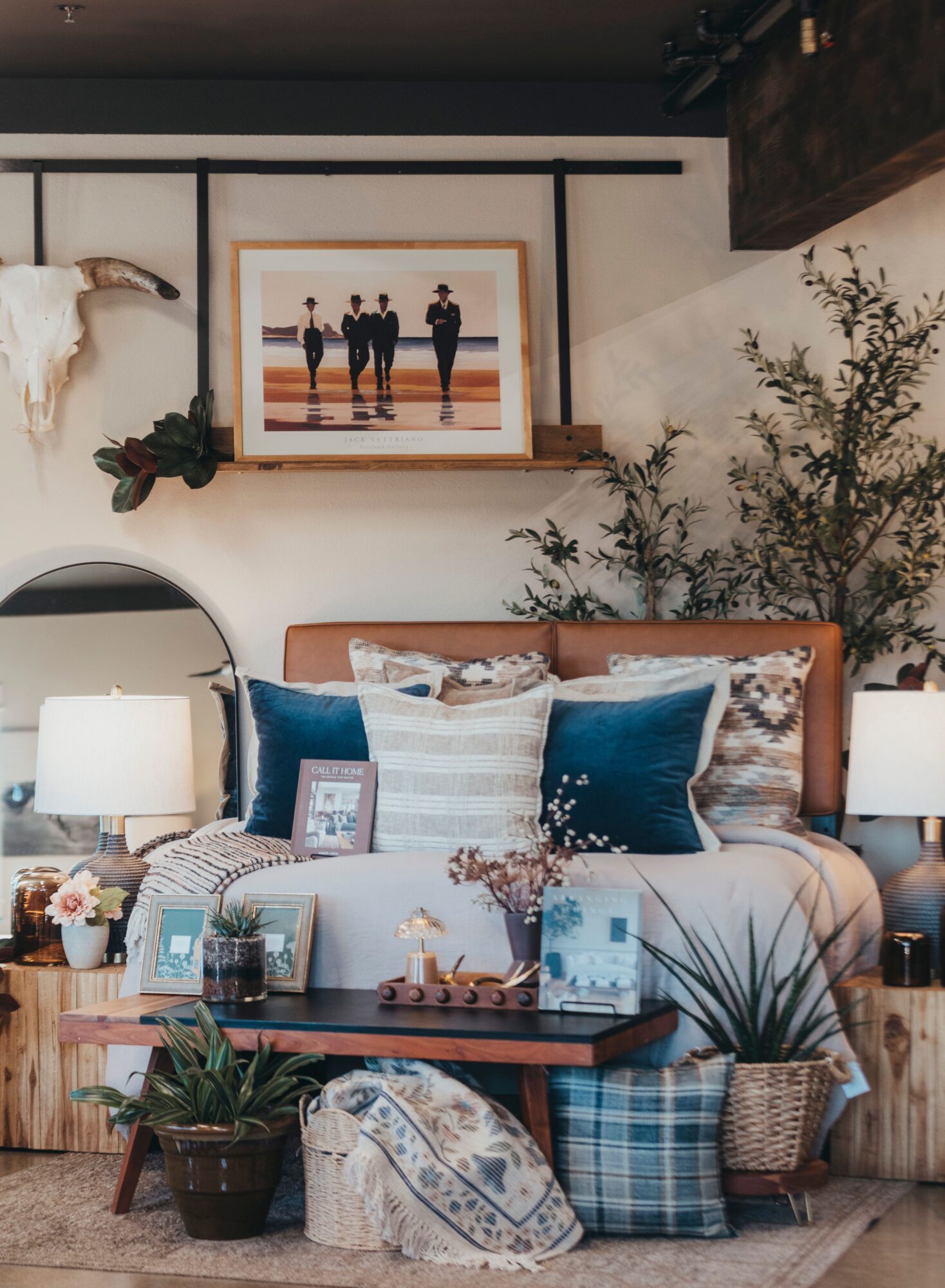 Cozy bedroom with framed photo, pillows, plants, and decorative items on a bed and side table.