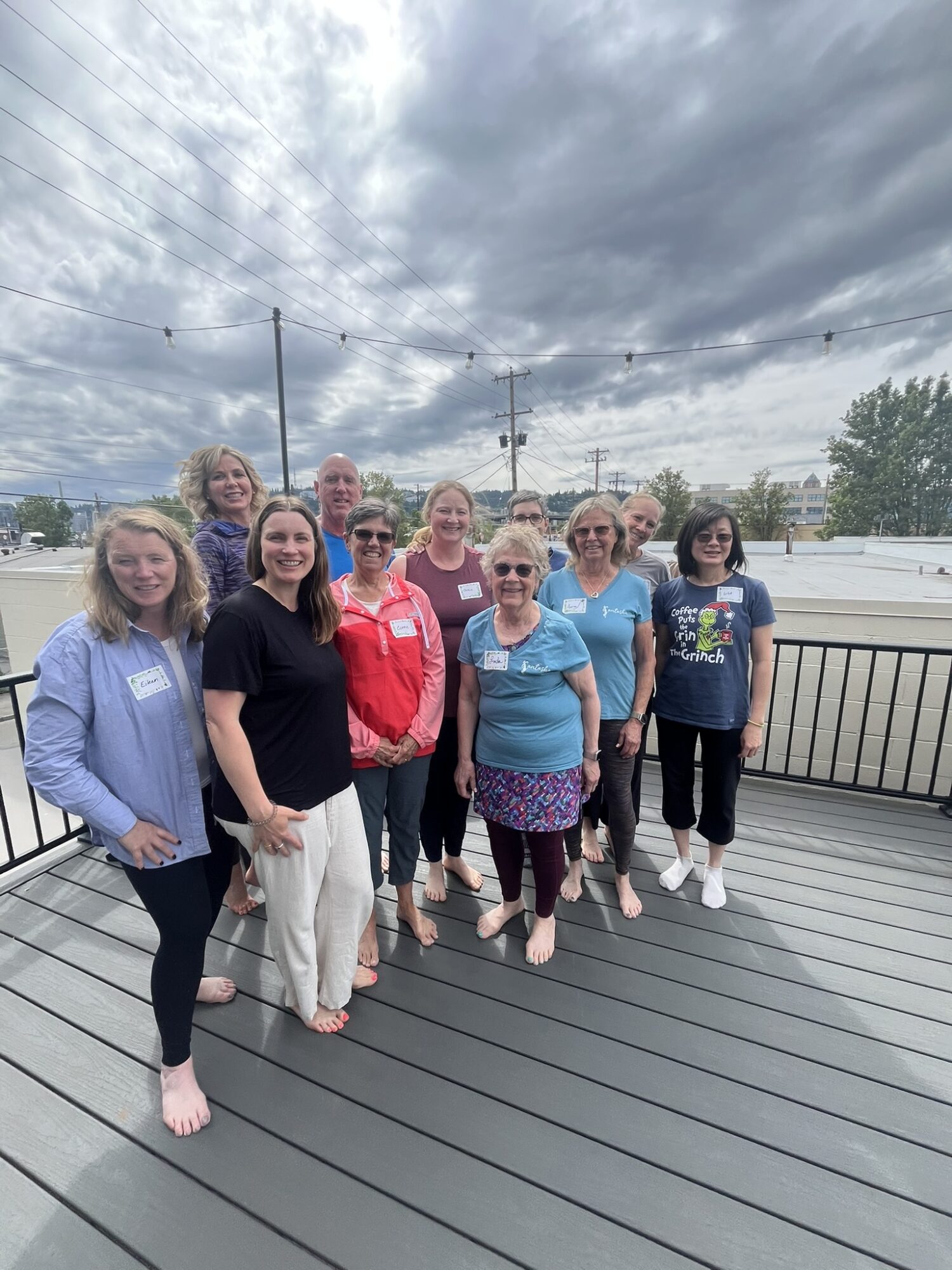 Group of ten women standing on a deck outdoors under cloudy sky, smiling at the camera.