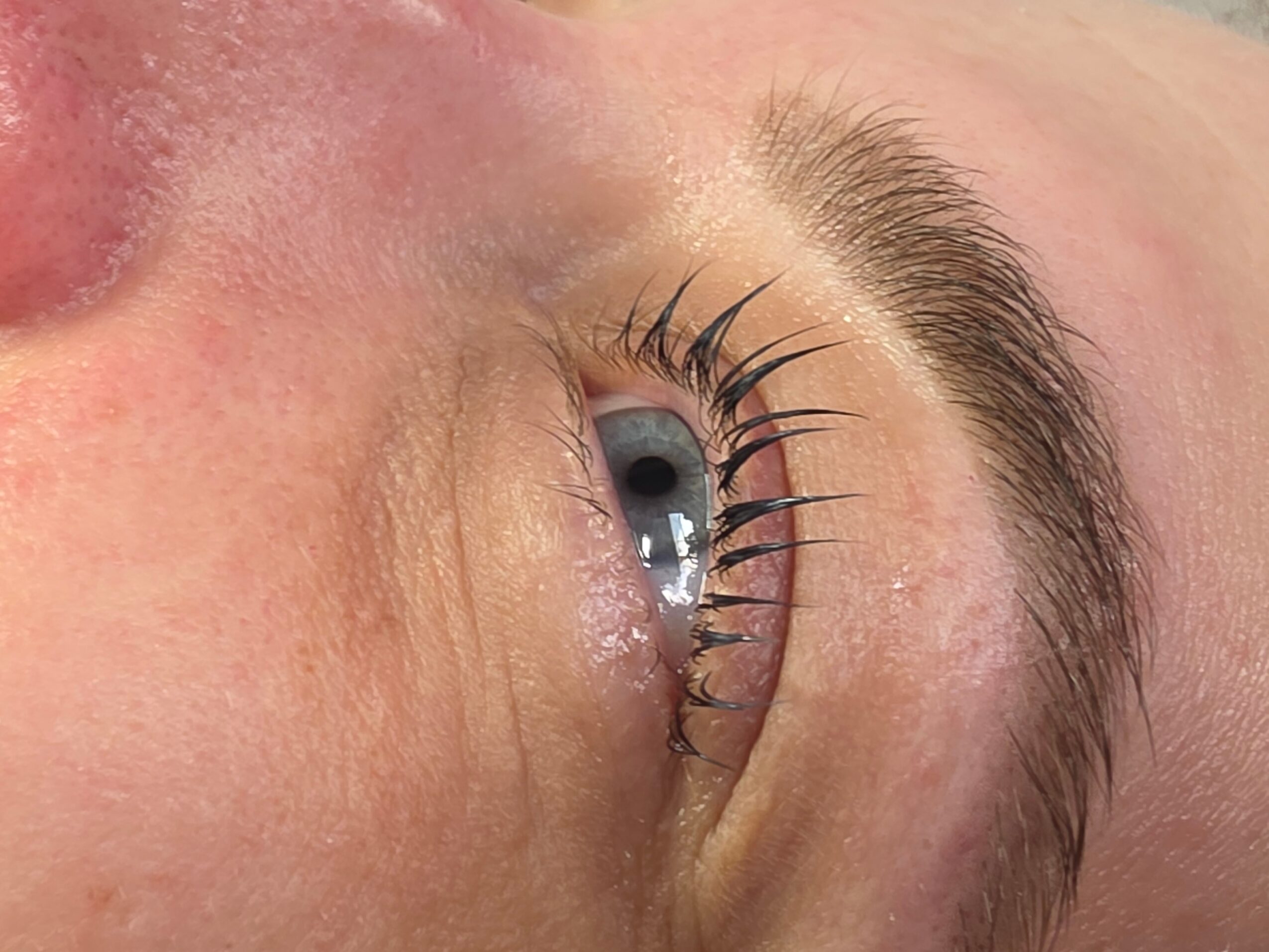 Close-up of a person's eye with visible eyelashes and eyebrow, showing the eye looking slightly upward.