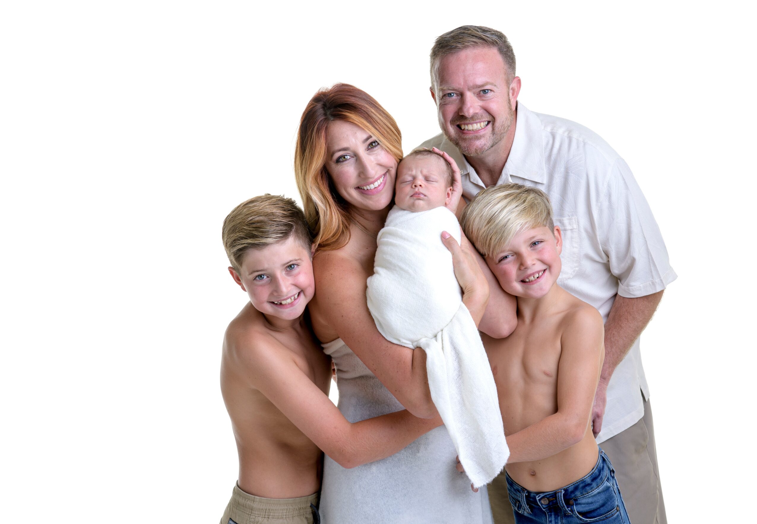 Family of five, including two children, a woman, a man, and a newborn, smiling together against a white background.