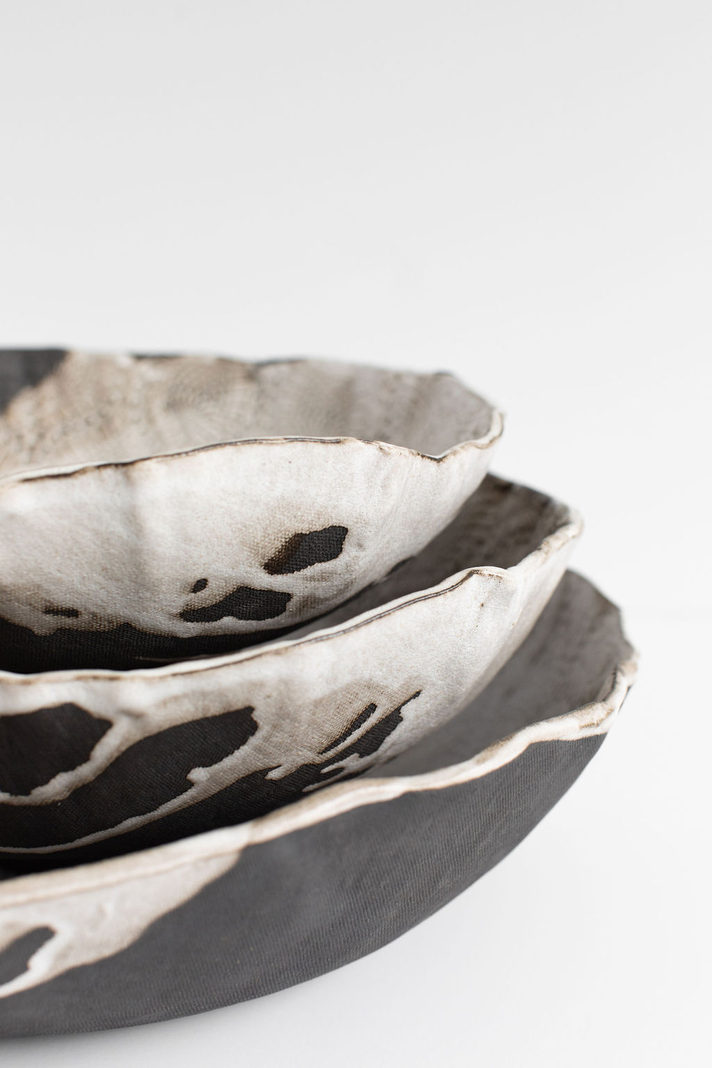 Close-up of stacked ceramic bowls with black and white patterns, against a plain white background.