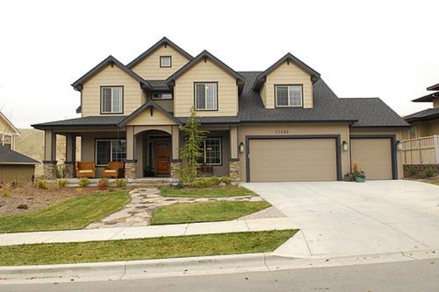 Two-story house with a front porch, driveway, and landscaped yard, under a cloudy sky.