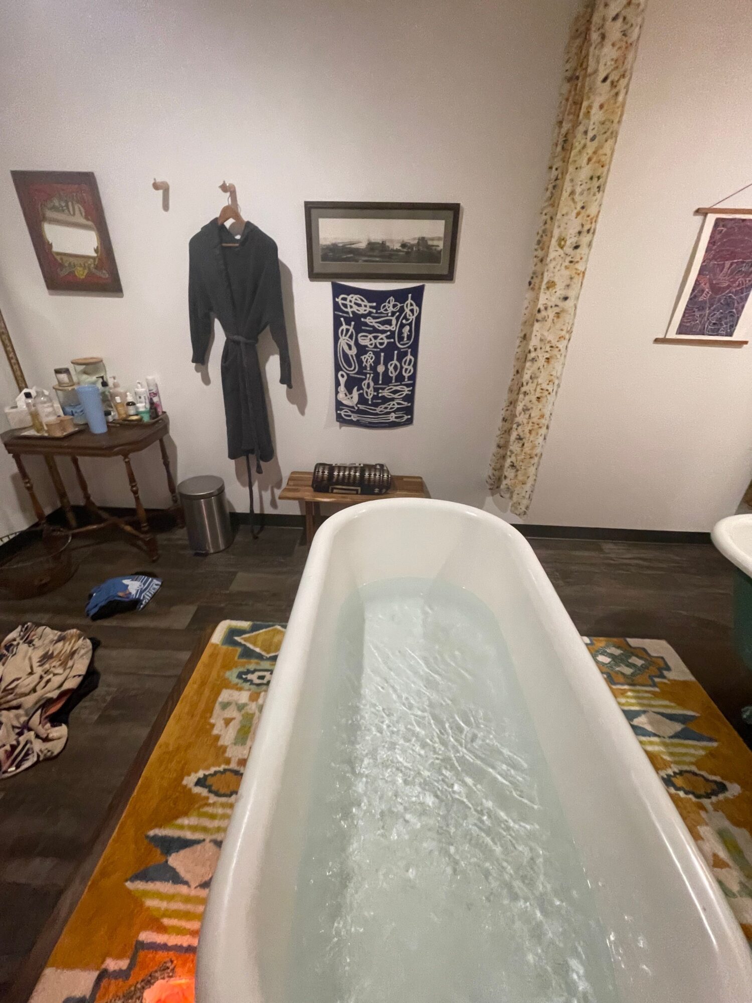 Bathroom with bathtub, dark wood floor, and wall decorations, viewed from above with the tub on the right side.