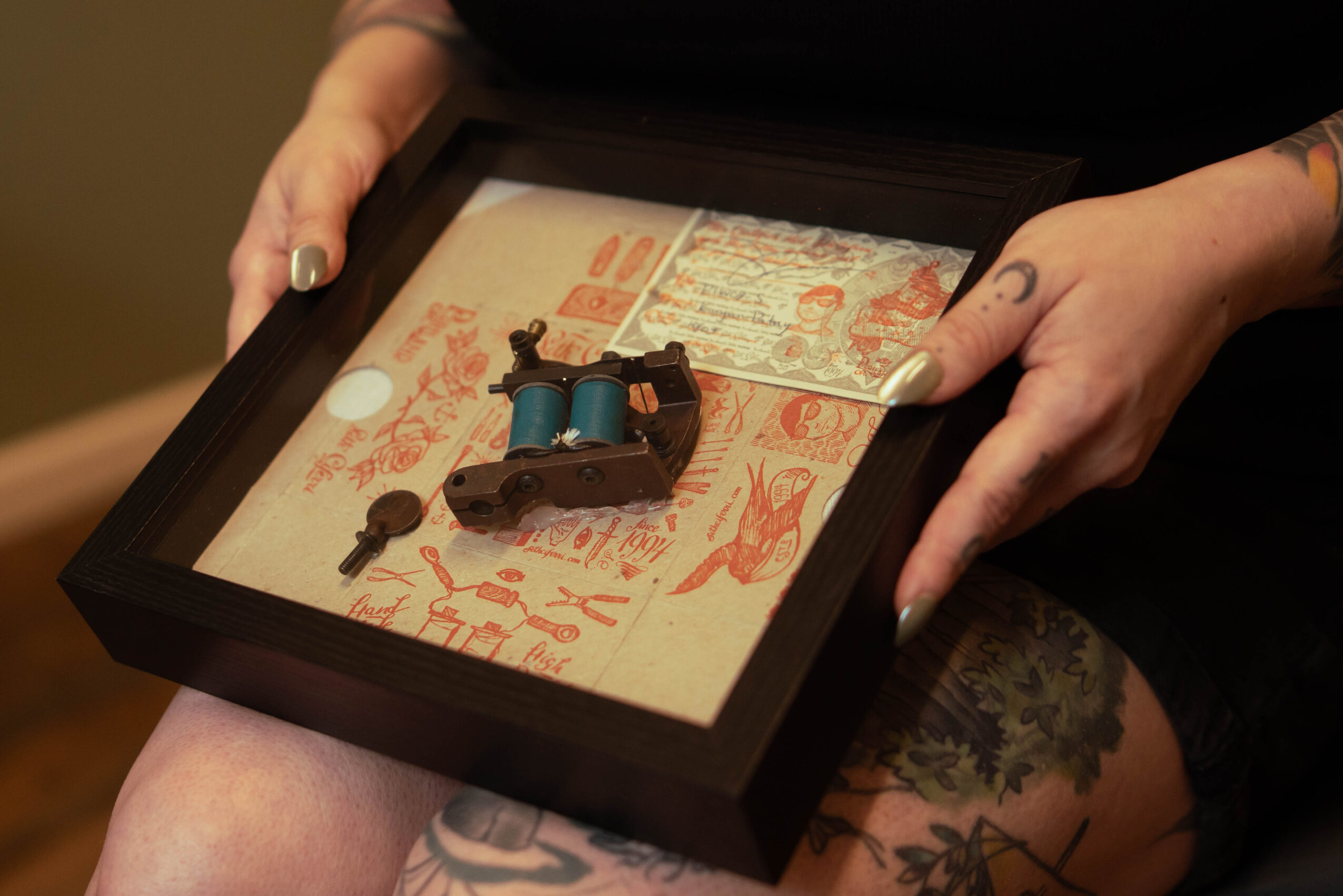 Person holding a shadow box with a small model of a train and decorative paper background.