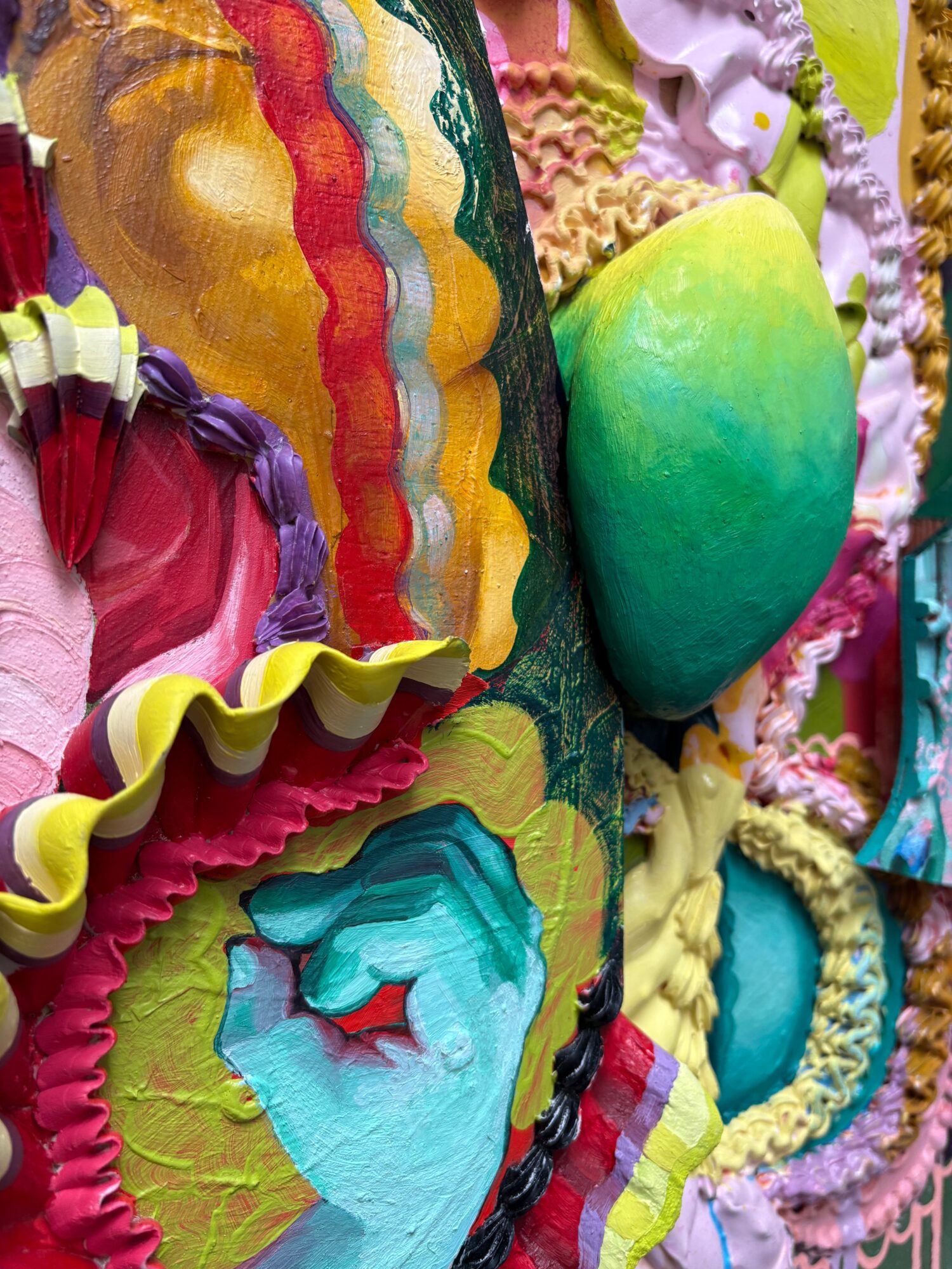 Colorful, textured decorations with ruffles, wavy patterns, and a large green and yellow object, possibly a cake or sculpture.