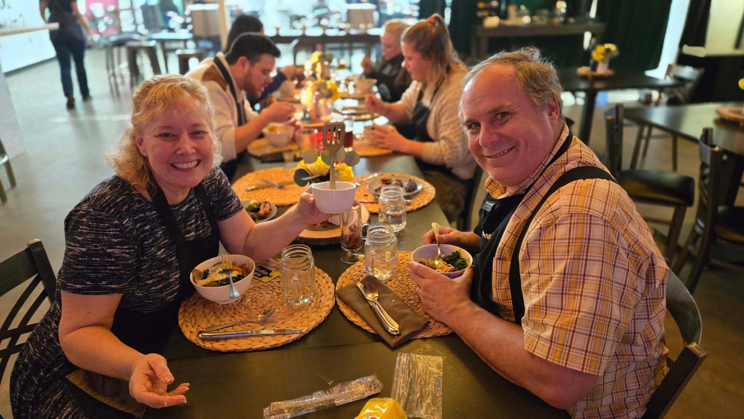 People sitting at a table enjoying food and drinks in a restaurant, smiling and engaging with each other.