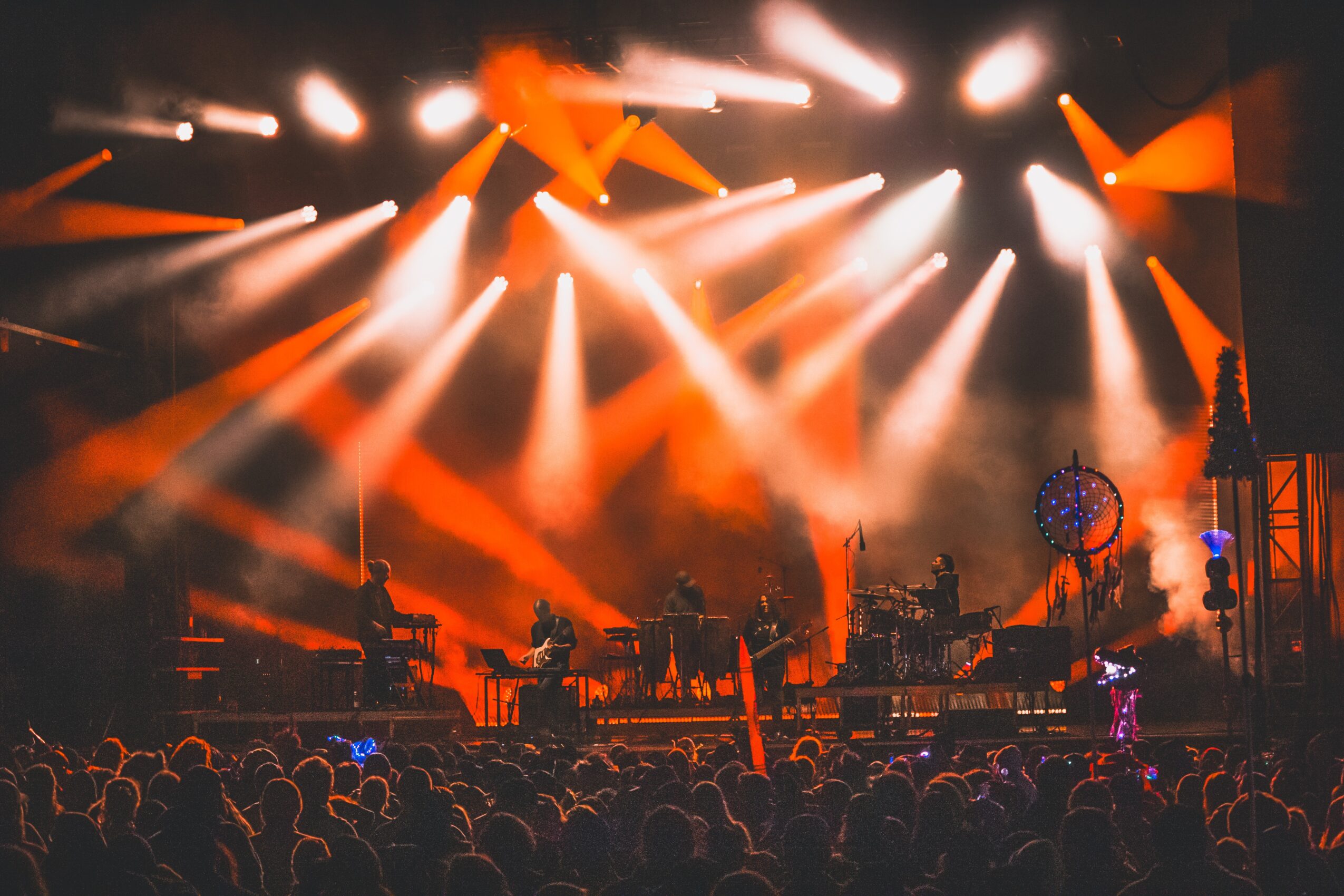 Stage with bright orange and white lights, musical instruments, and a crowd watching a concert.
