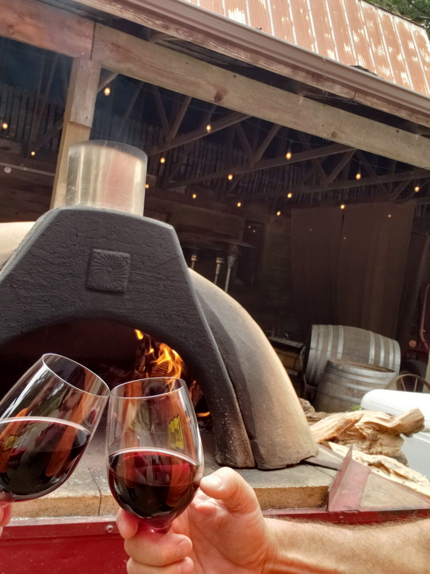 Person pouring red wine into a glass at a bar or restaurant, with a window and interior visible in the background.